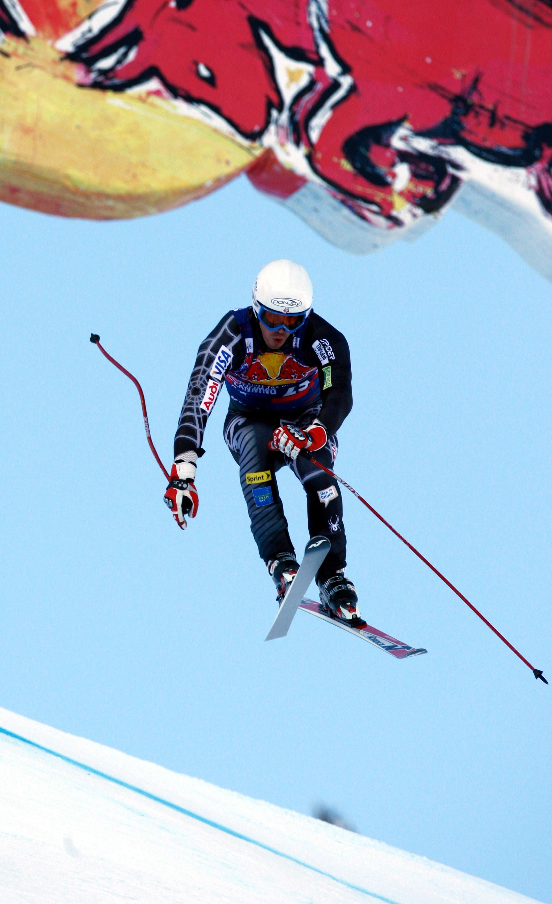 Skirennläufer springt bei Abfahrtstraining in Kitzbühel mit Red Bull Banner im Hintergrund.