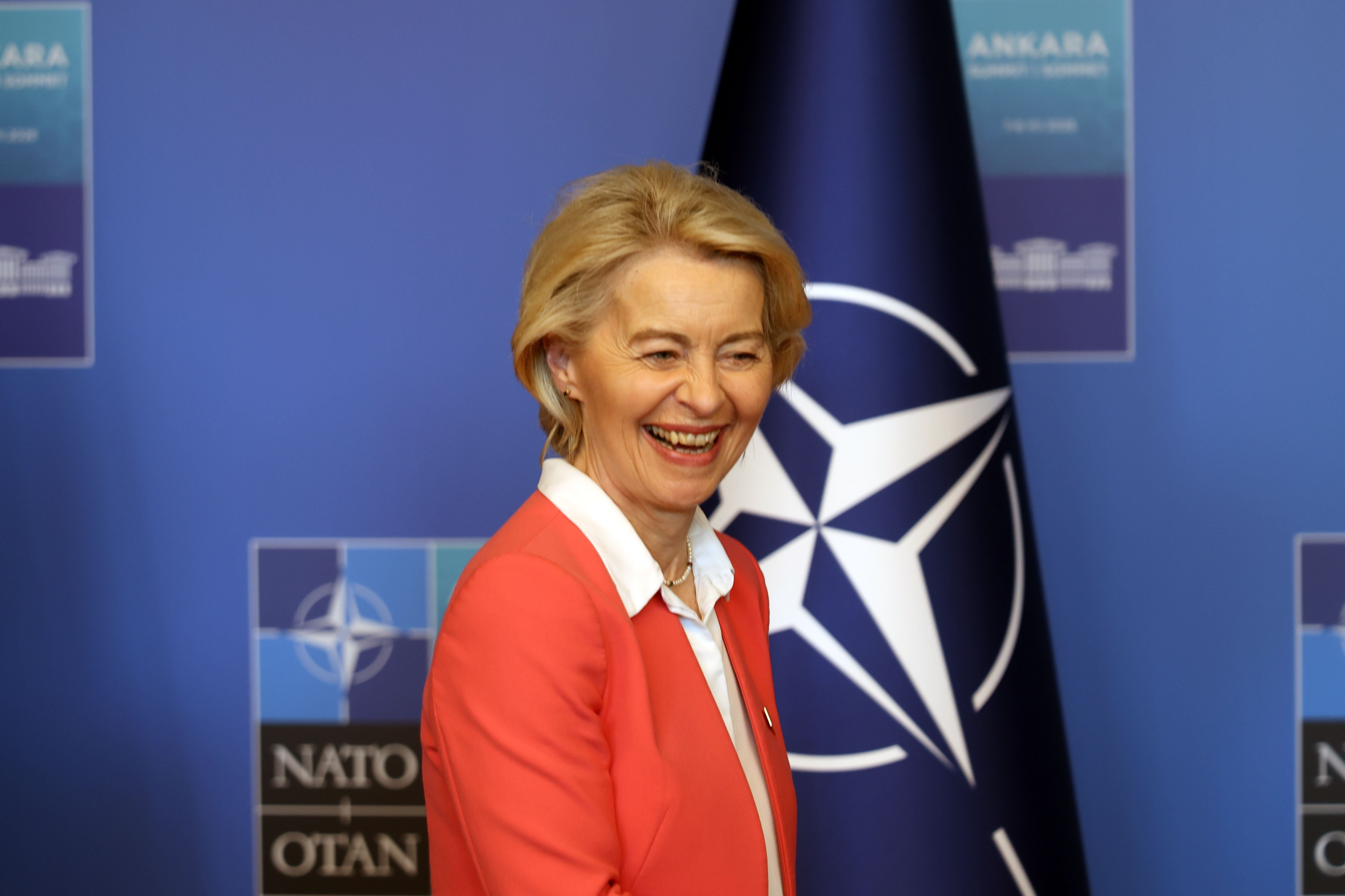 Eine lachende Frau steht vor einer NATO-Flagge bei einer Konferenz in Ankara.