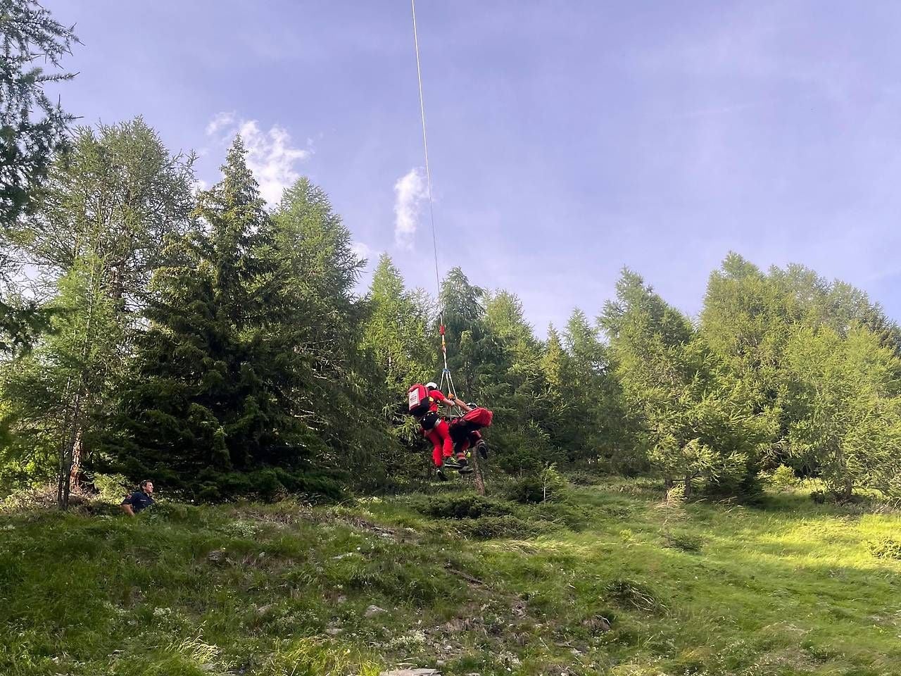 Bergretter seilen verletzten Jäger im Wald per Seilwinde ab.