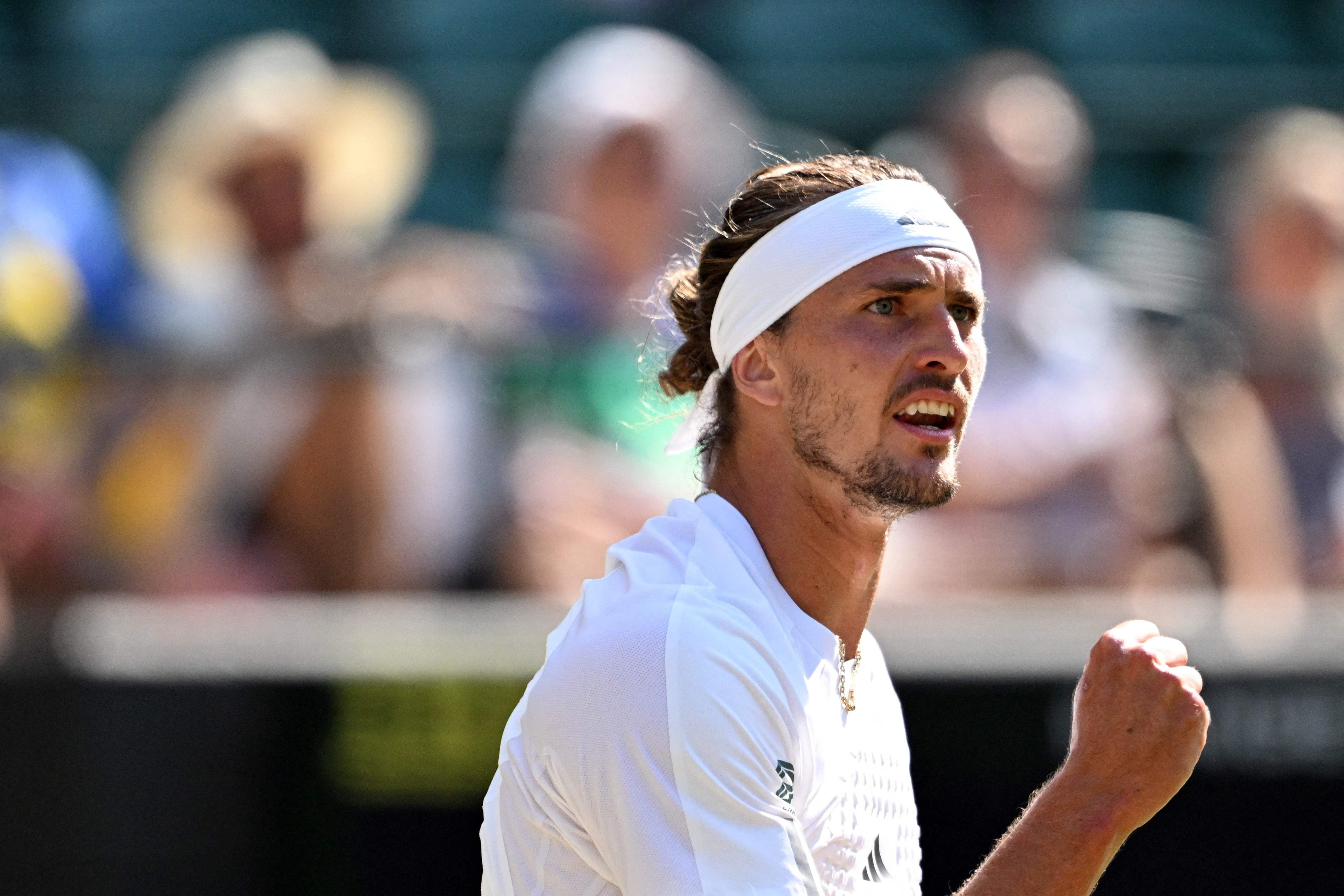 Tennisspieler mit weißem Stirnband ballt die Faust während eines Spiels auf dem Tennisplatz.