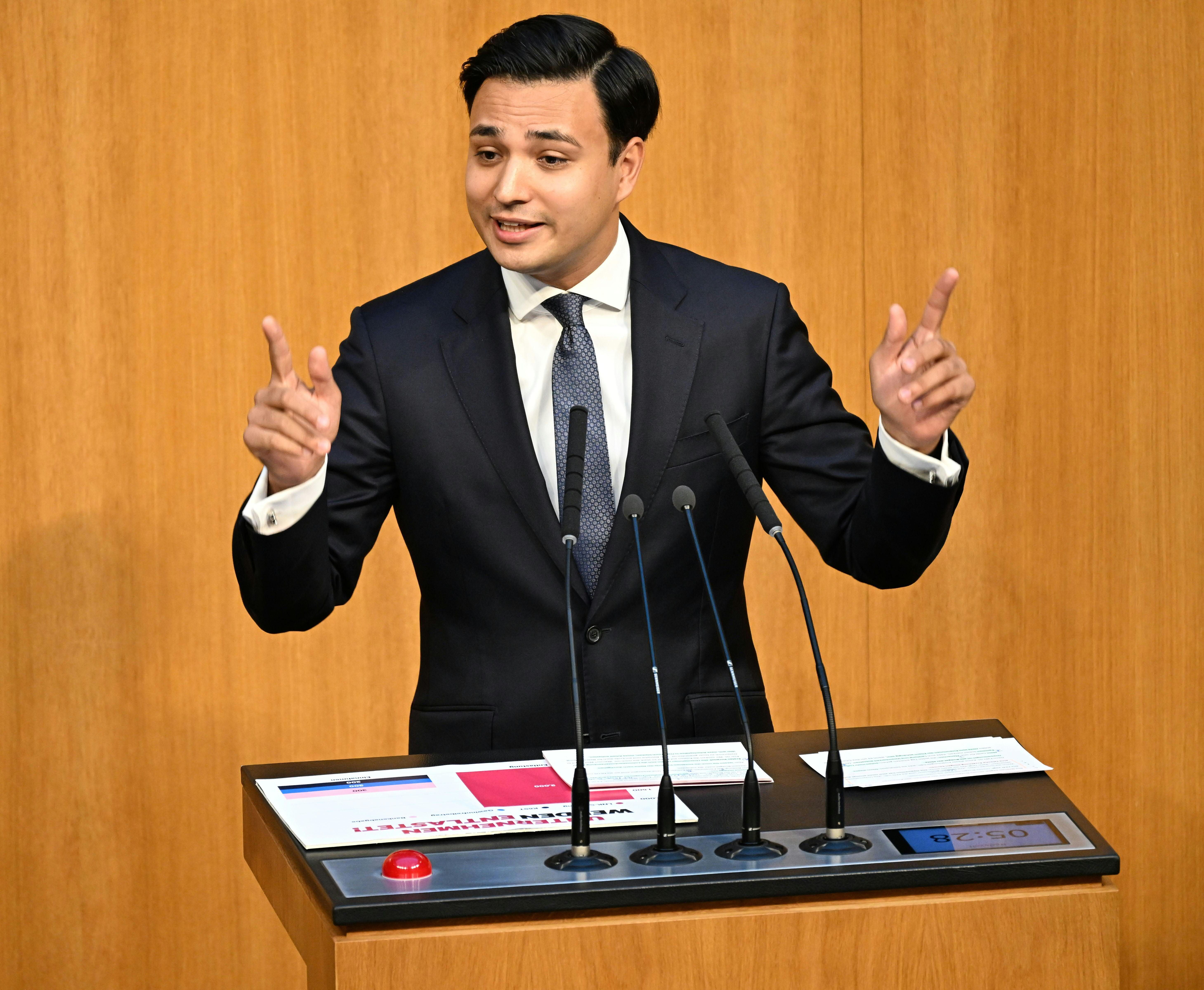Ein Mann im Anzug spricht gestikulierend an einem Rednerpult im österreichischen Parlament.