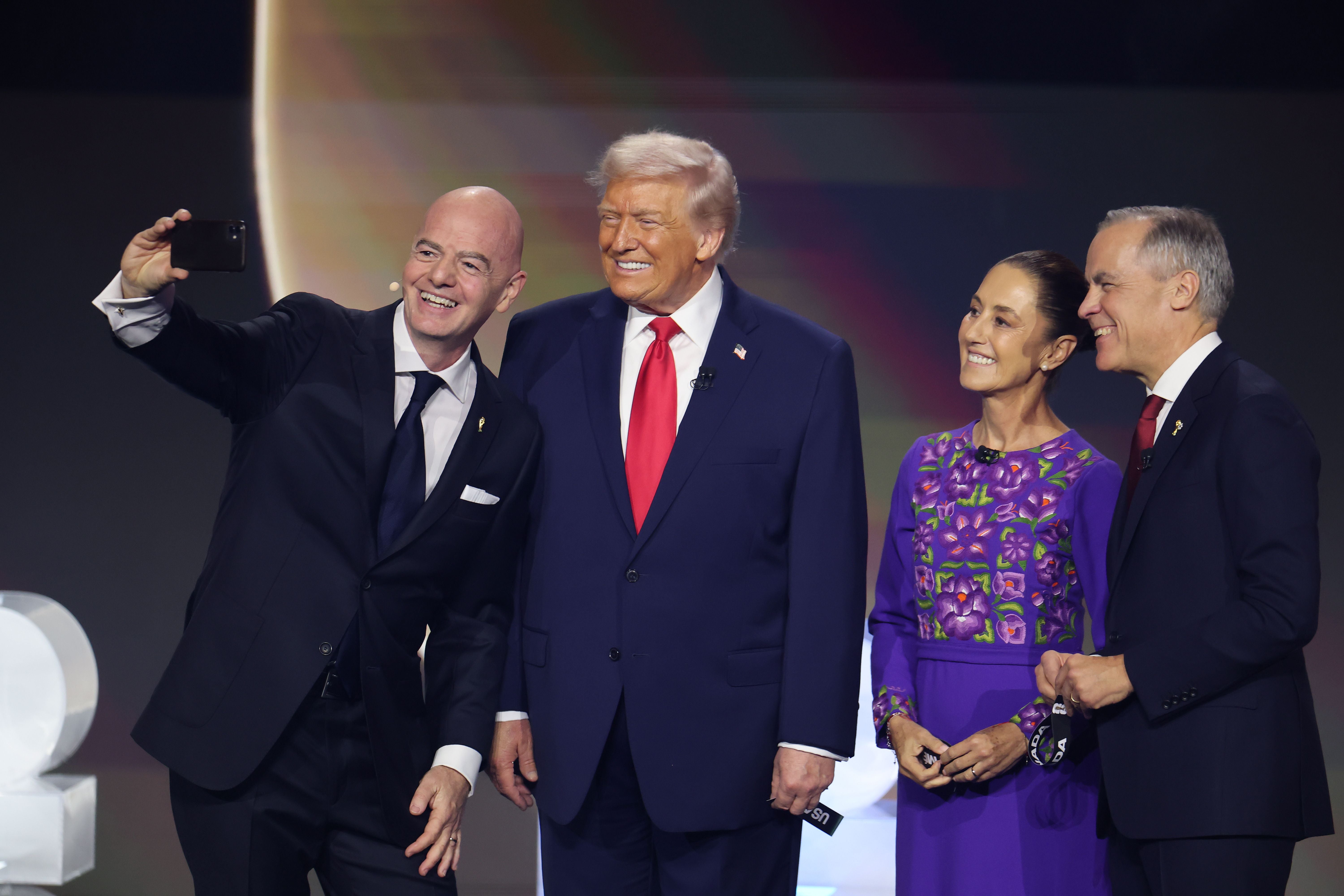 Gianni Infantino macht im Anzug ein Selfie mit Donald Trump, der ein dunkelblaues Sakko und eine rote Krawatte trägt.