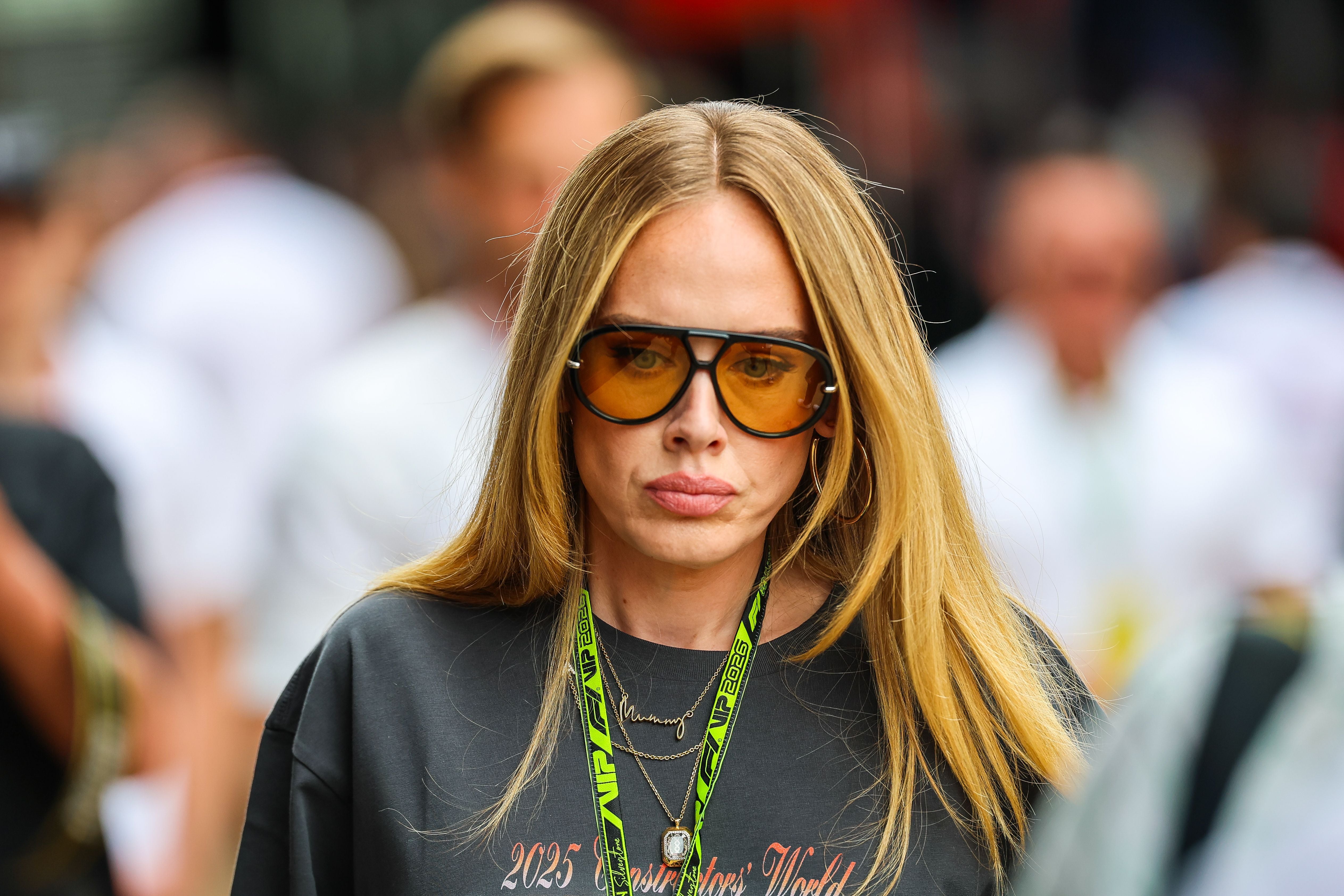 Frau mit langen blonden Haaren und großer Sonnenbrille läuft durch eine Menschenmenge.