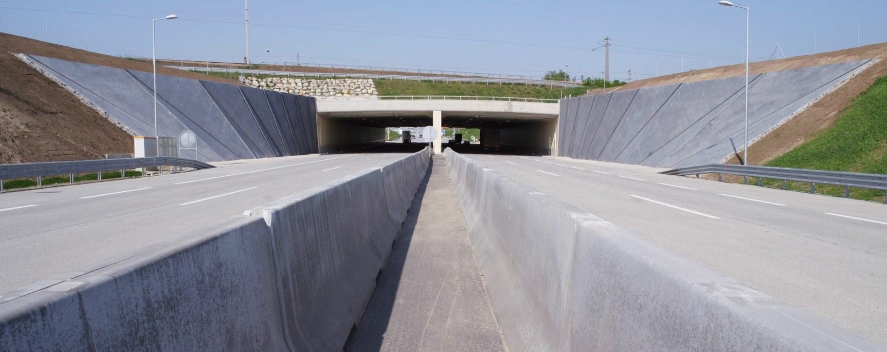 Einfahrt zum Lobautunnel mit breiten Fahrbahnen und Betonmauern an den Seiten.