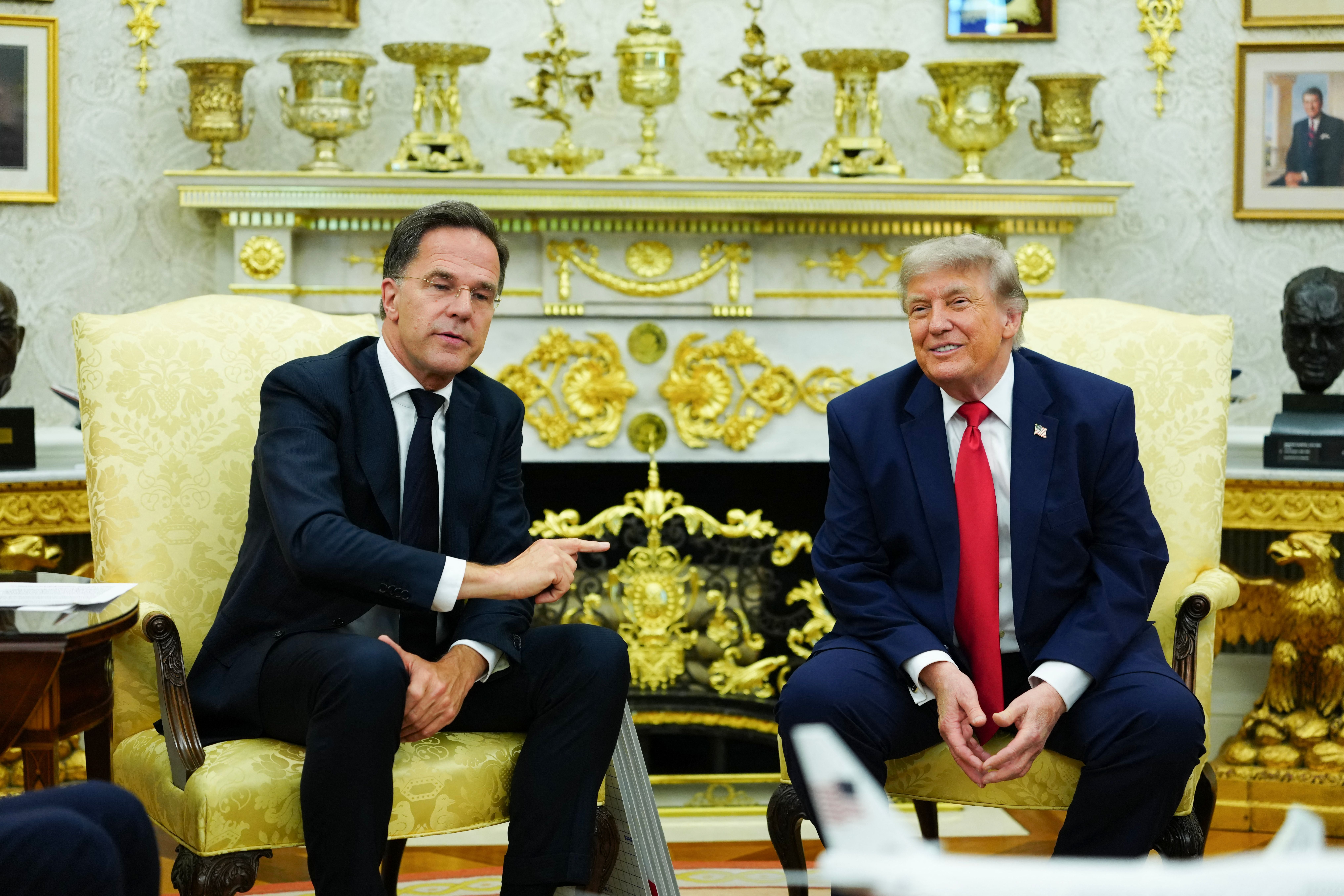 Zwei Männer im Anzug sitzen auf gelben Sesseln im prunkvollen Oval Office und unterhalten sich.