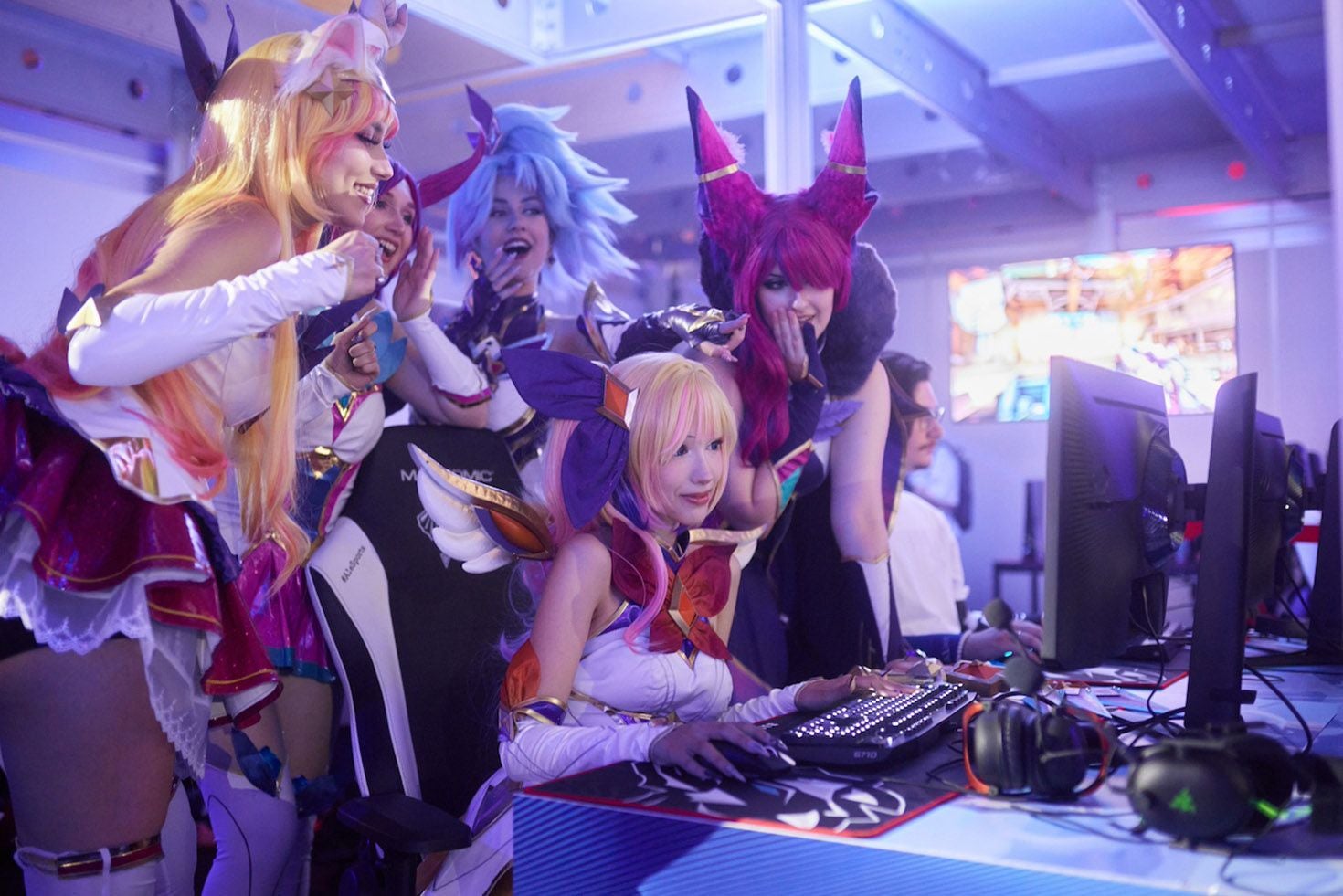 Mehrere Cosplayerinnen spielen begeistert an Computern auf einem Esportsfestival.