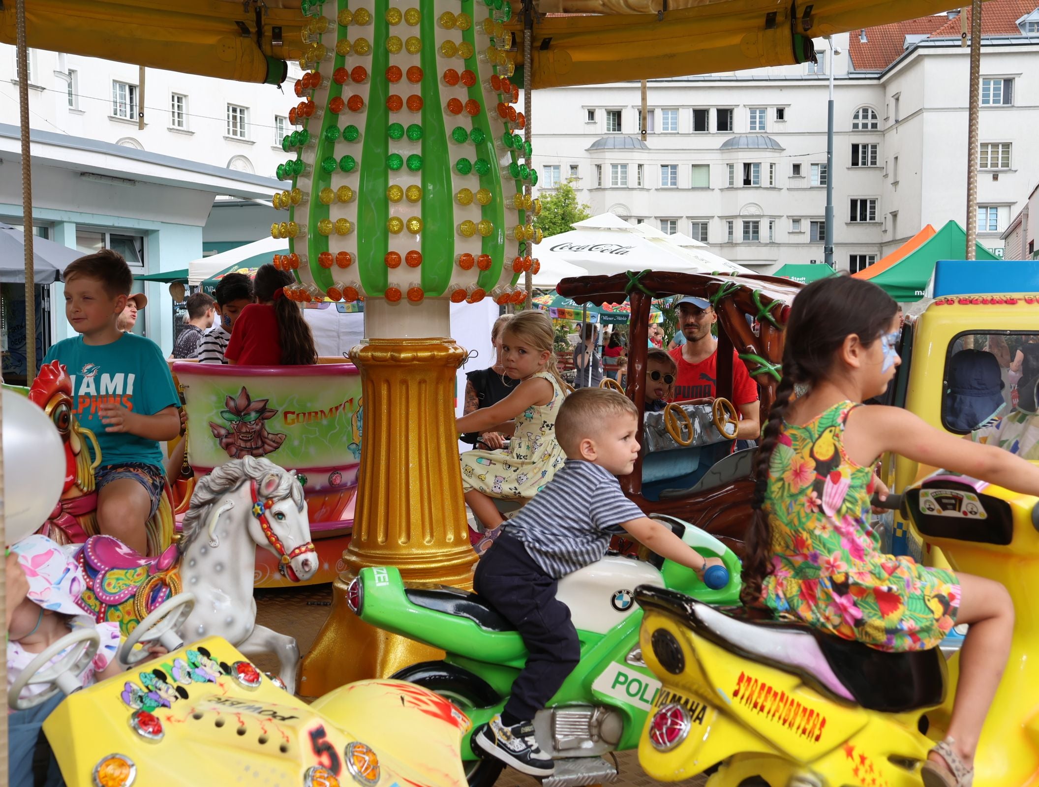 Kinder fahren auf einem Karussell mit bunten Fahrzeugen auf einem Jahrmarkt.
