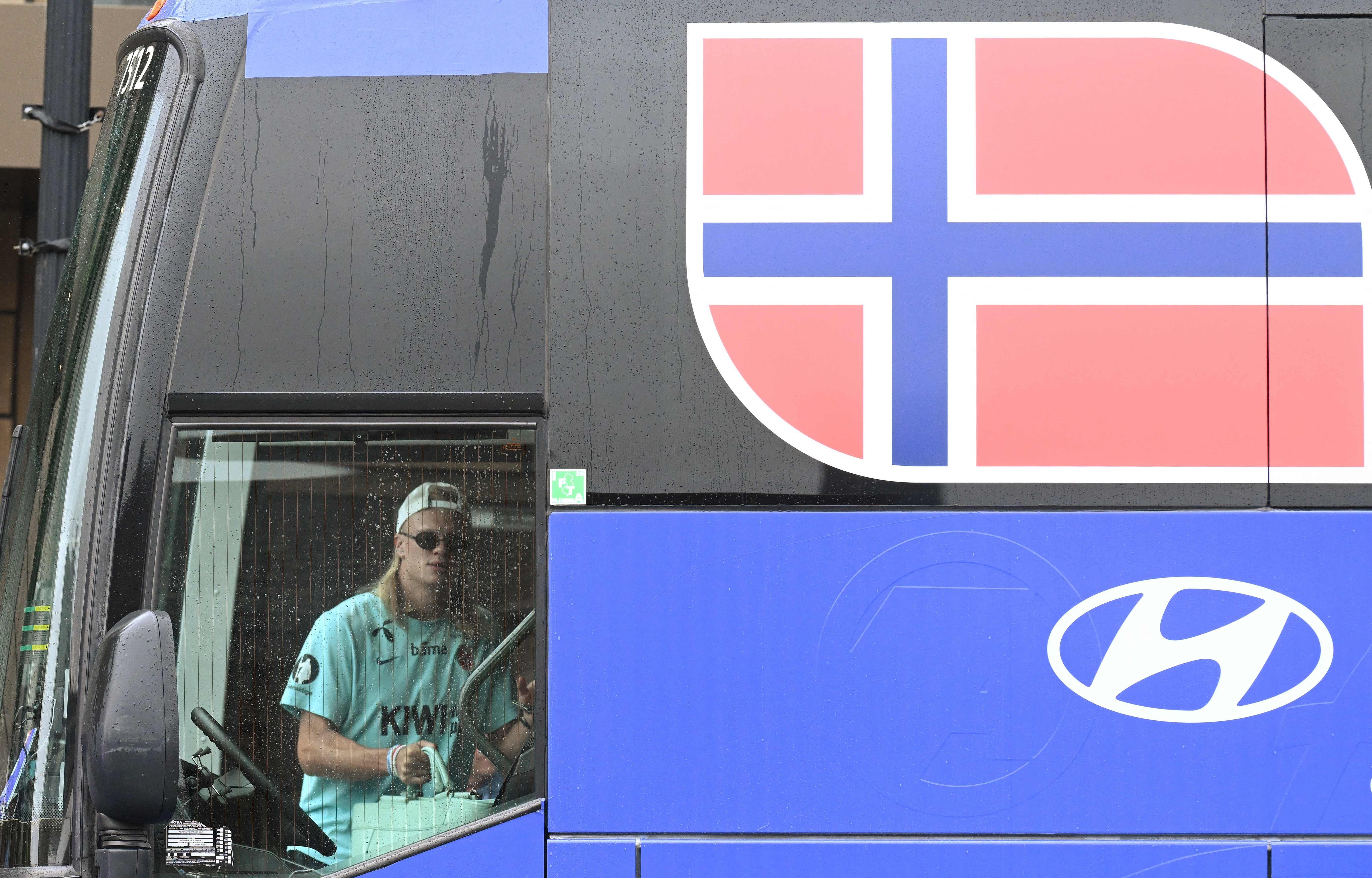 Ein Fußballspieler mit Sonnenbrille steigt in einen Bus mit norwegischer Flagge und Hyundai-Logo.
