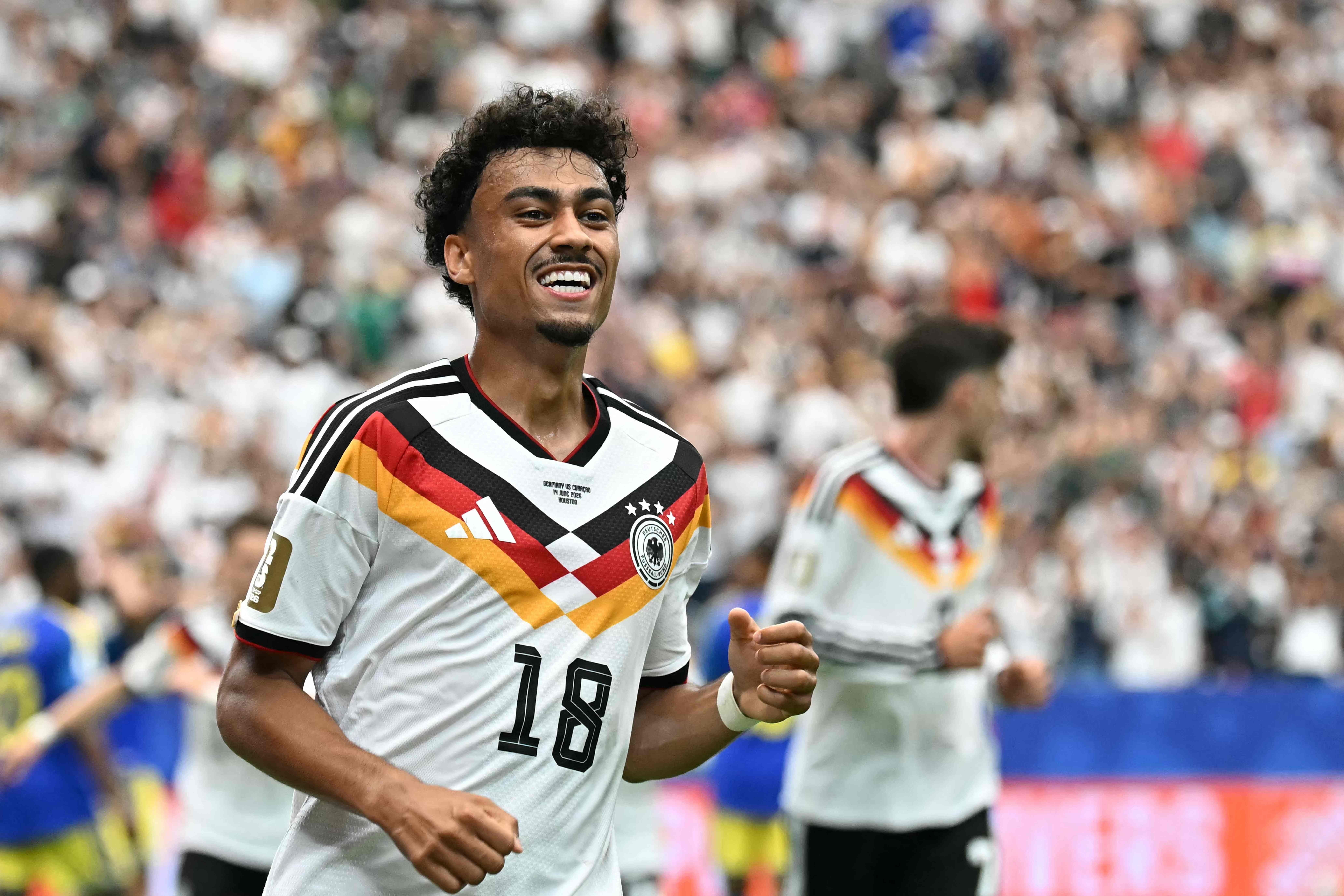 Fußballspieler im Deutschland-Trikot jubelt nach einem Tor, Zuschauer im Hintergrund.