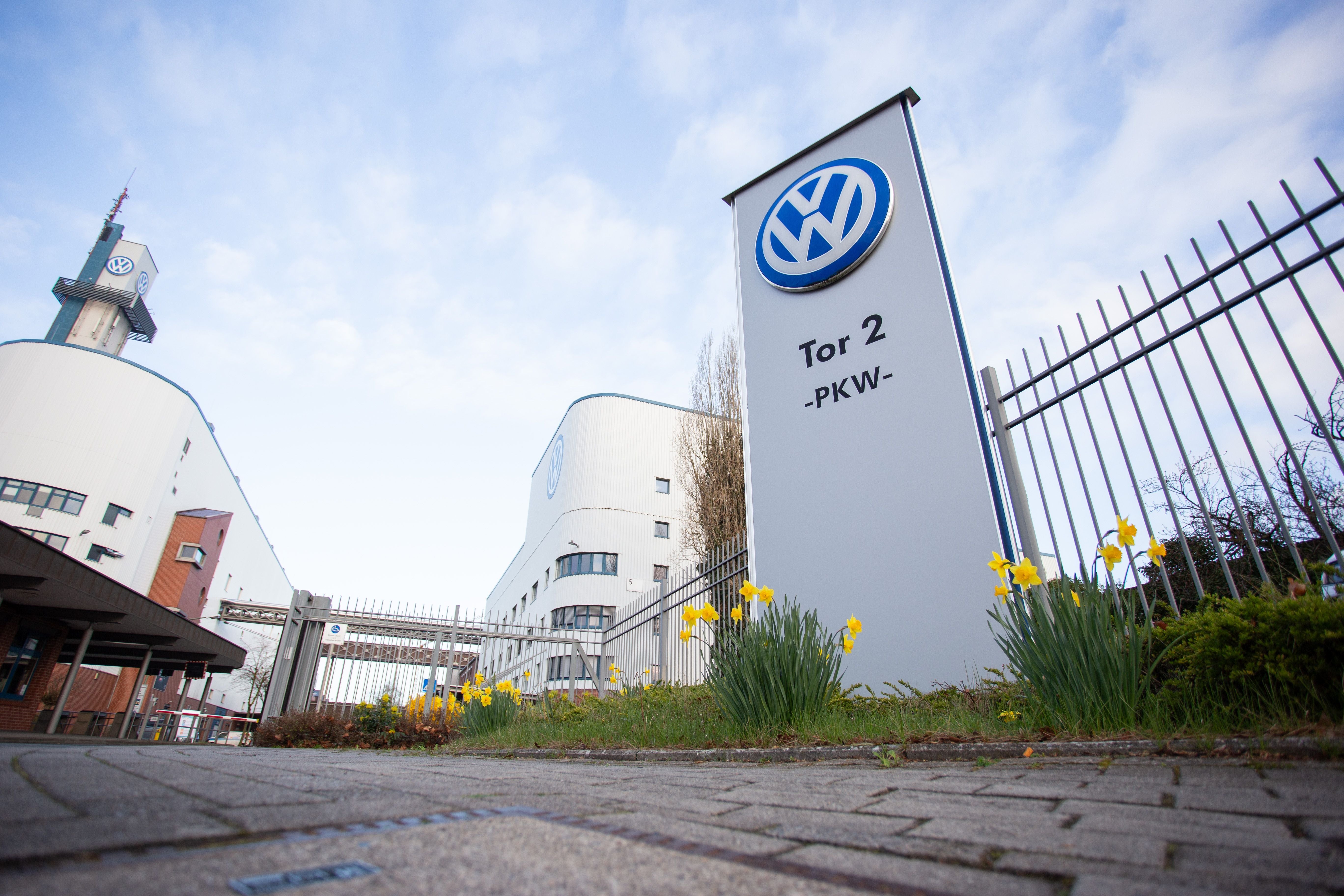 Eingangstor des Volkswagen-Werks Osnabrück mit VW-Logo und blühenden Narzissen im Vordergrund.