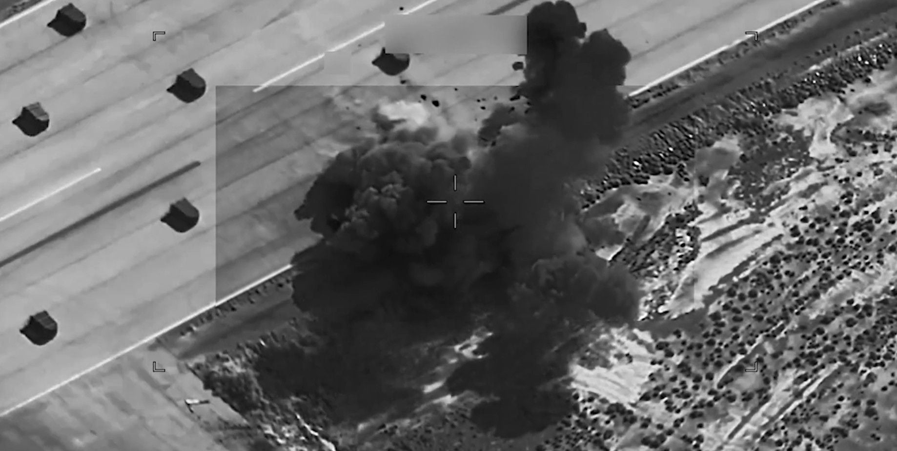US-Angriffe: Schwarz-Weiß-Luftaufnahme einer Explosion mit Rauchwolke neben einer Straße im Iran.