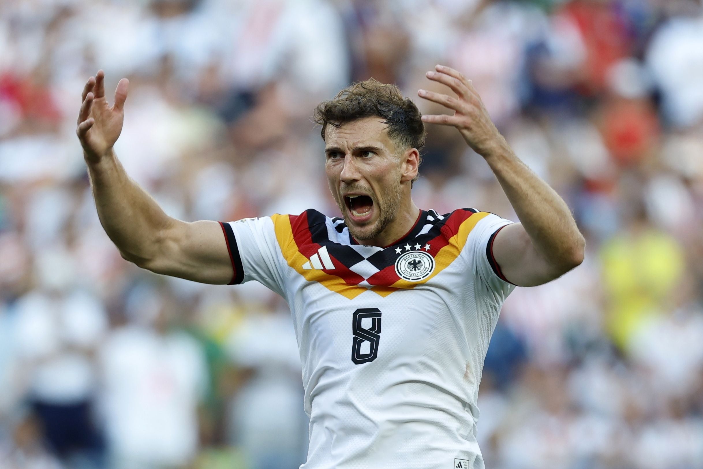 Ein Fußballspieler der deutschen Nationalmannschaft gestikuliert emotional auf dem Feld.