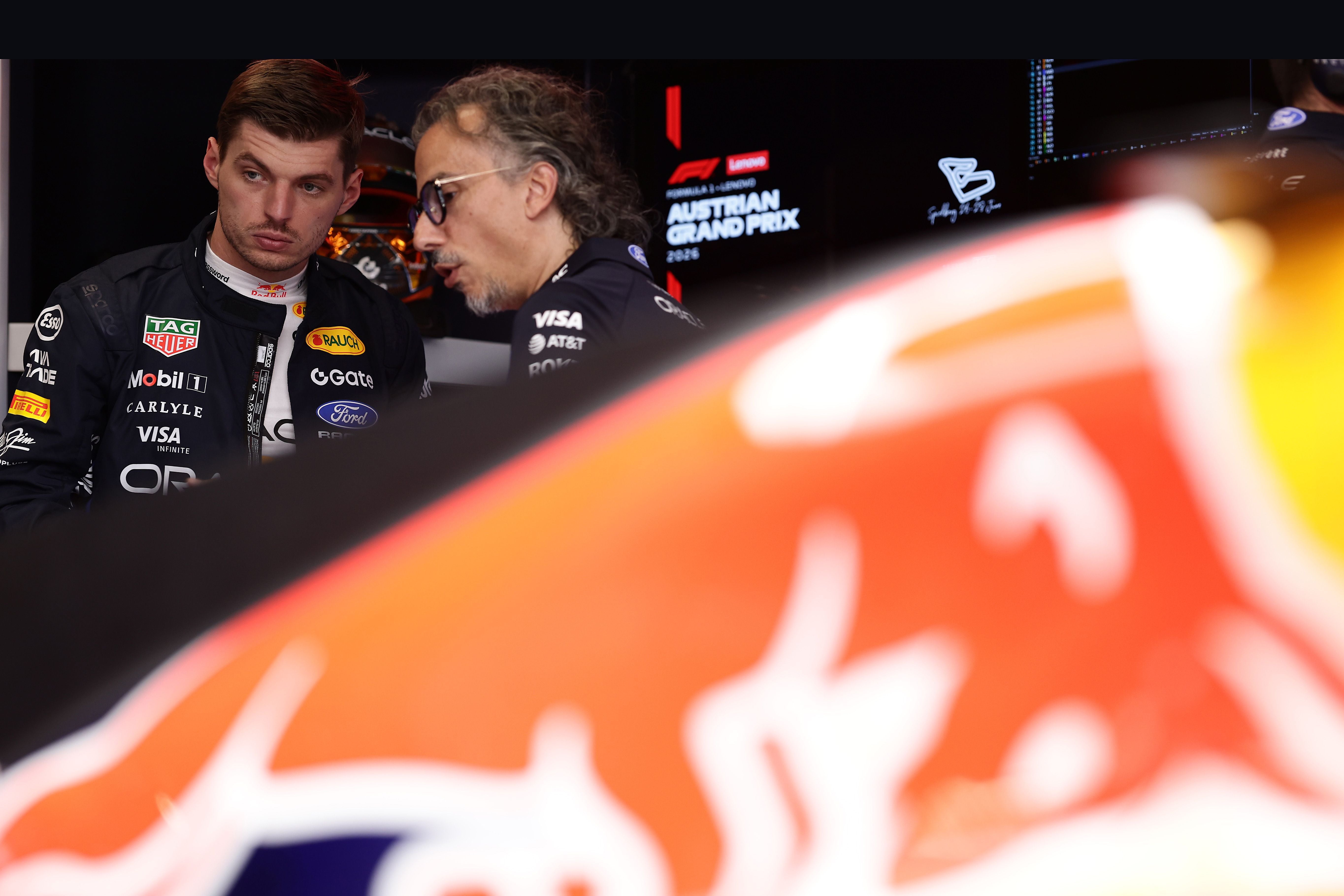 Zwei Männer im Red Bull Racing Outfit sprechen in einer Formel-1-Garage, ein Auto im Vordergrund.