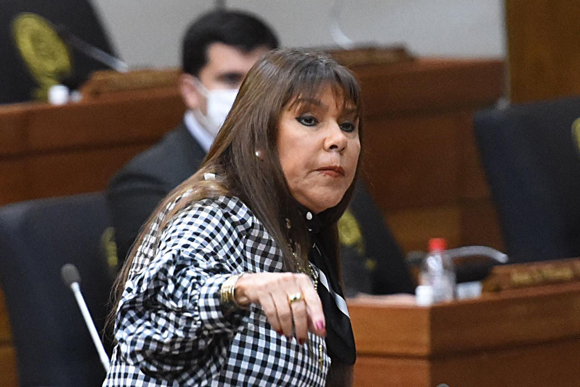 Celeste Amarilla spricht in einem Sitzungssaal vor Mikrofonen.
