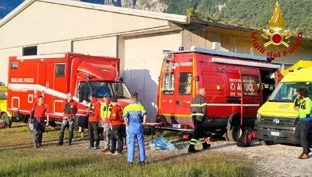 Mehrere Feuerwehrleute stehen vor Einsatzfahrzeugen bei einem Gebäude im Freien.