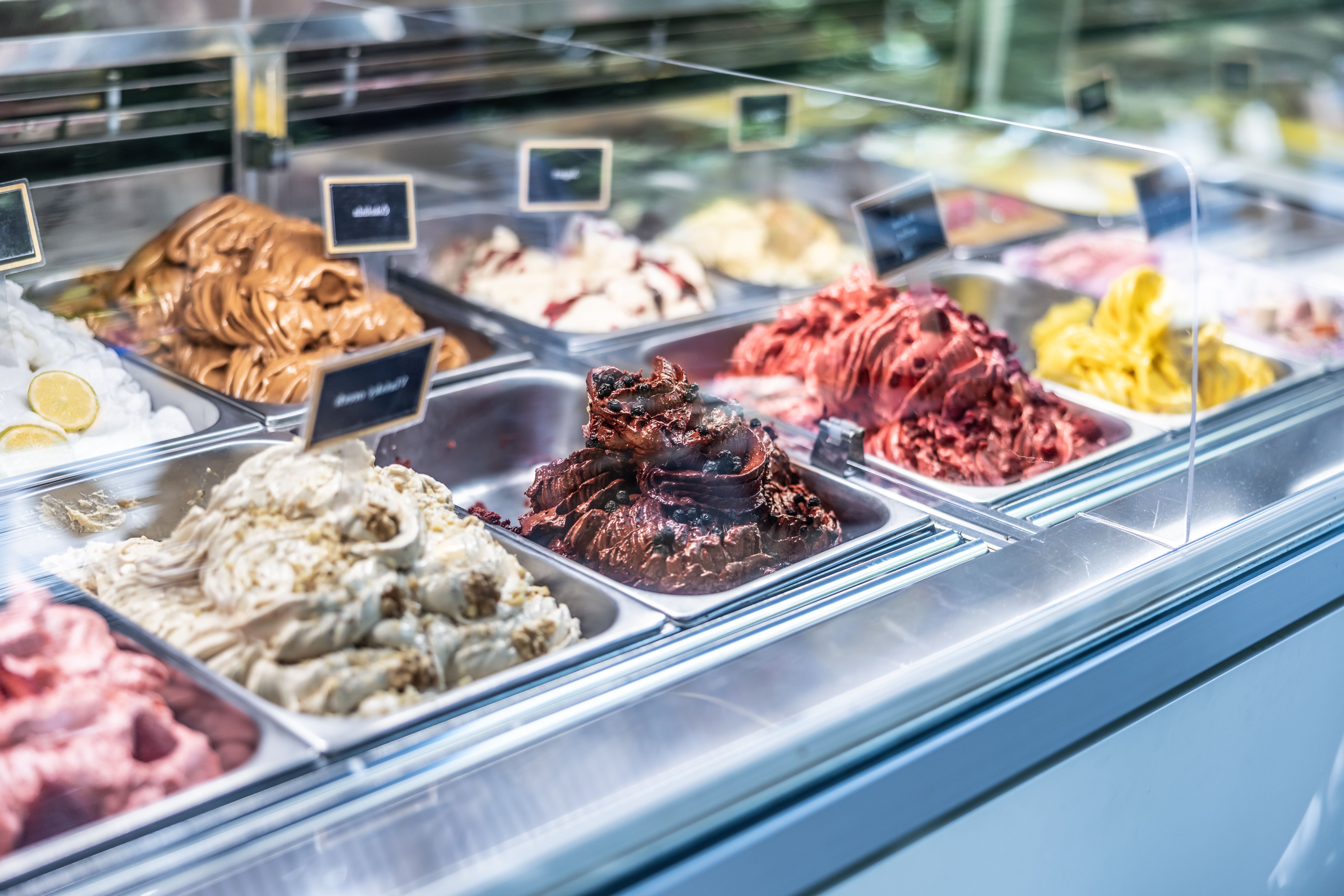Verschiedene Sorten Eiscreme und Sorbet in einer Eistheke hinter Glas ausgestellt.