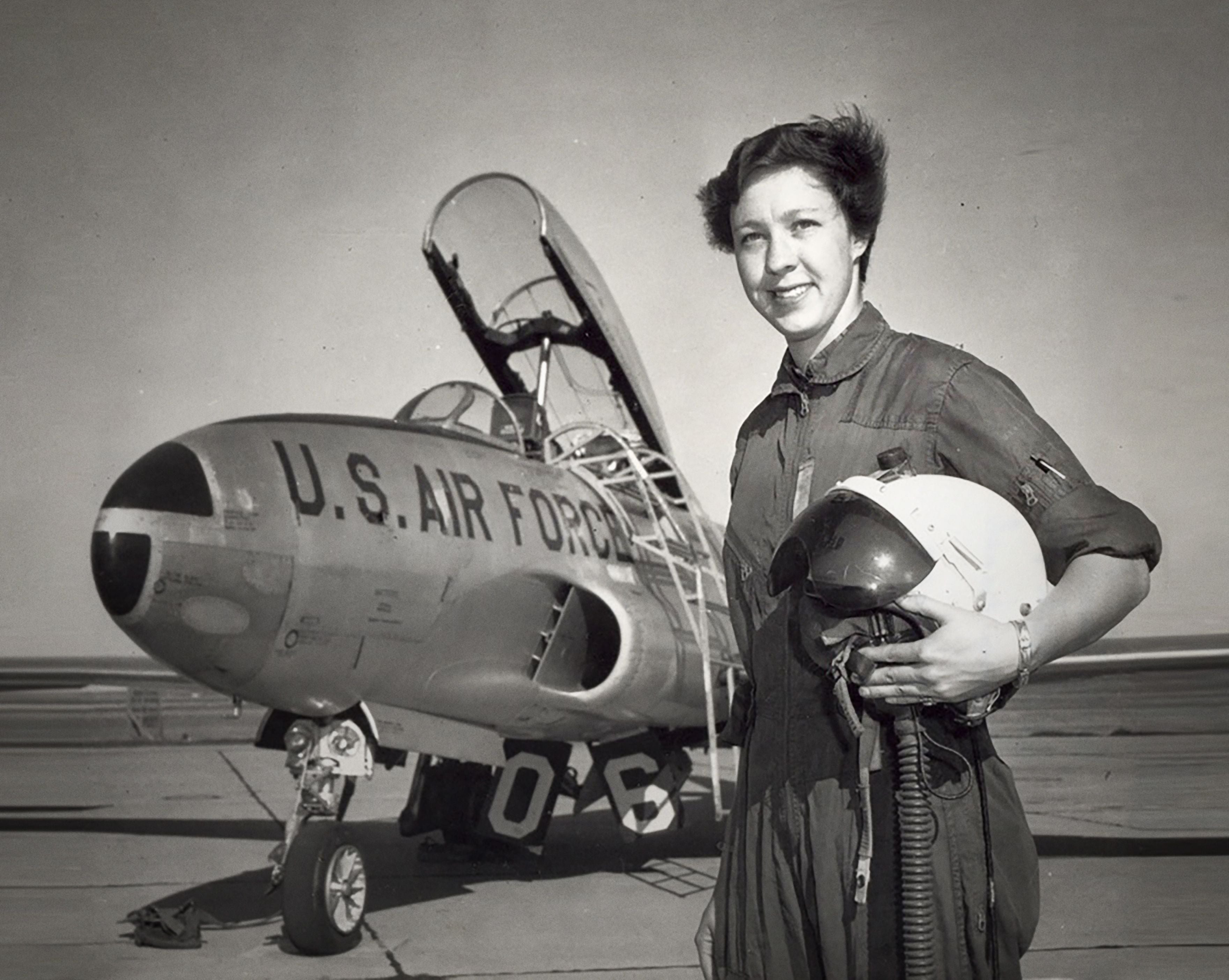 Pilotin Wally Funk steht mit Helm vor einem U.S. Air Force Flugzeug auf dem Rollfeld.