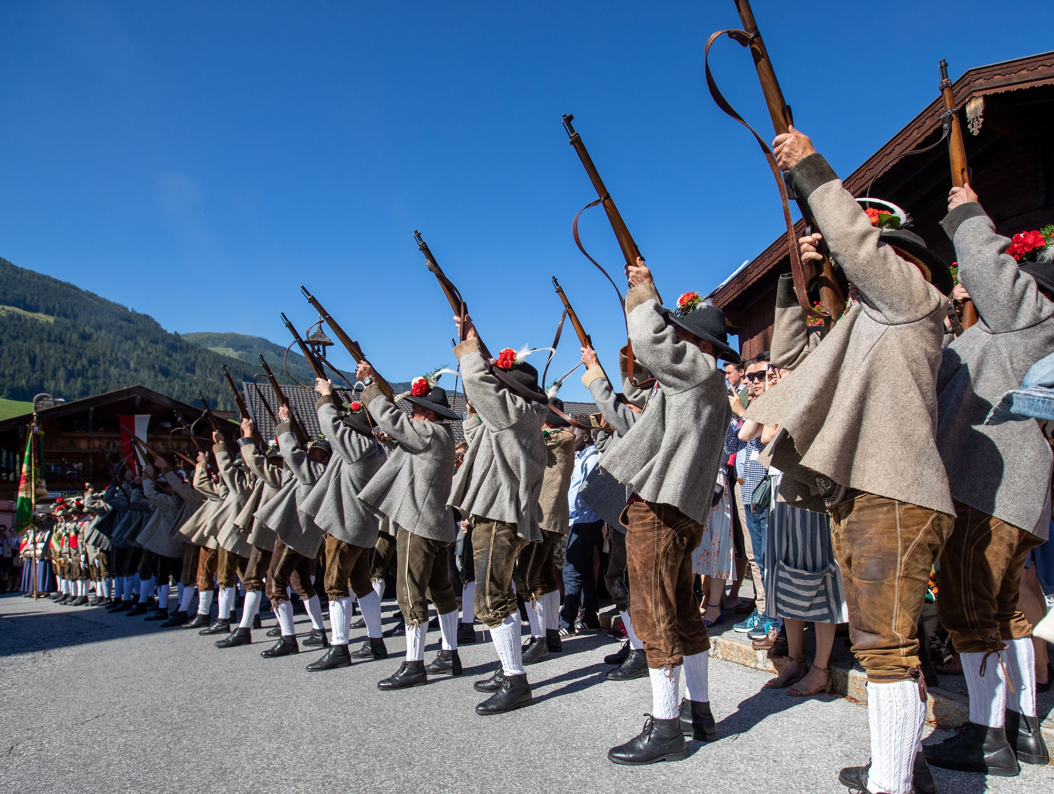 Drei Männer in Tiroler Tracht gehen bei einer Demo auf der Brennerautobahn Richtung Menschenmenge.