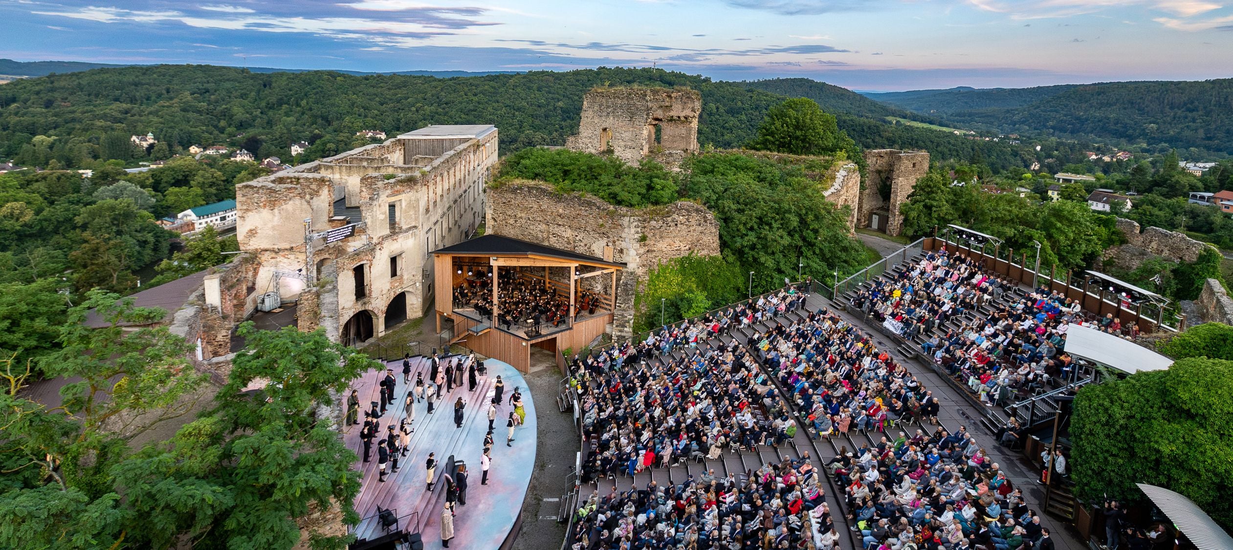 Freiluftaufführung vor Publikum in der Burgruine Gars mit Orchester und Darstellern auf der Bühne.