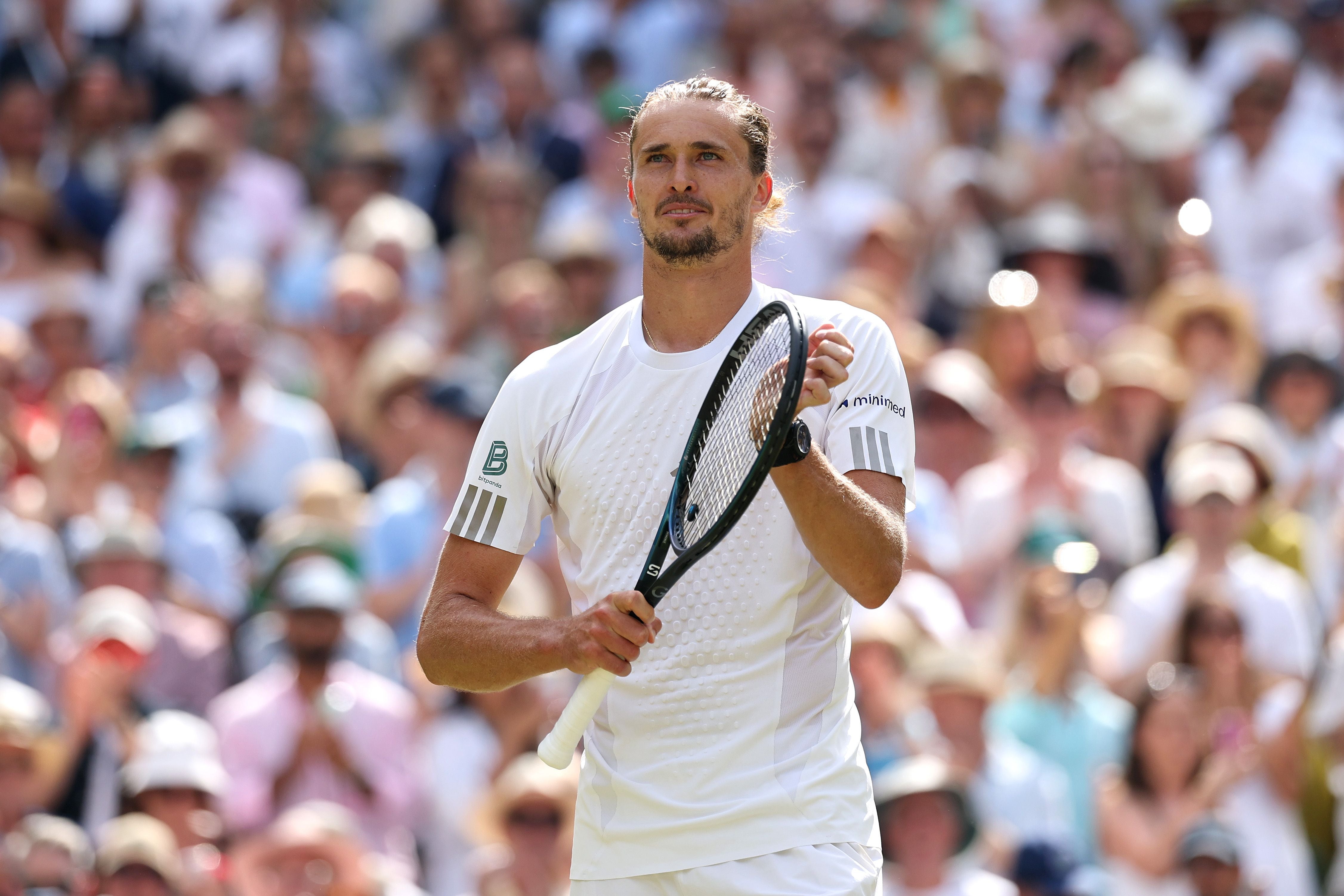 Ein Tennisspieler applaudiert mit Schläger in der Hand vor einem jubelnden Publikum.