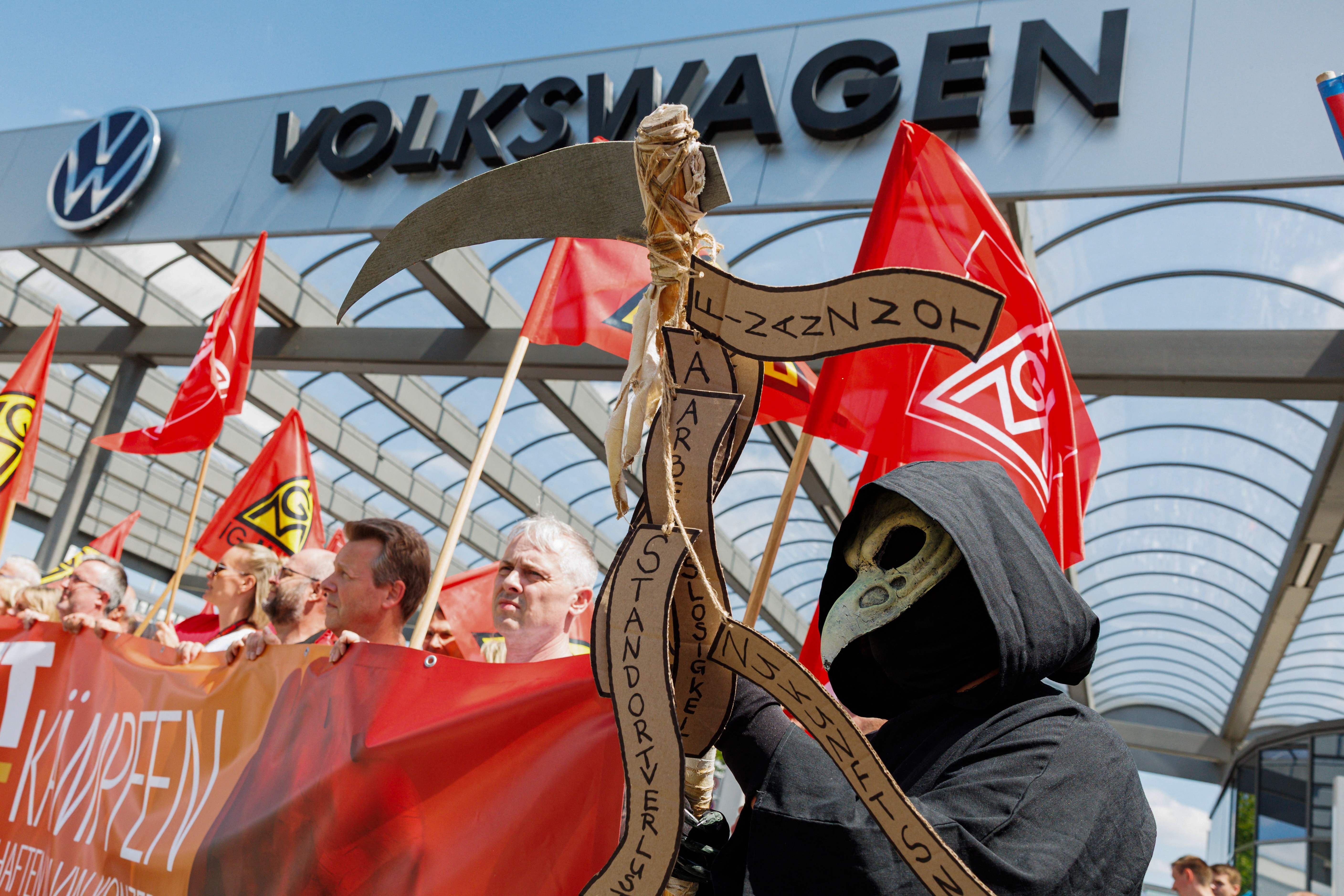 Demonstration vor einem Volkswagen-Werk mit IG Metall-Fahnen und einer Grim-Reaper-Kostümierung.