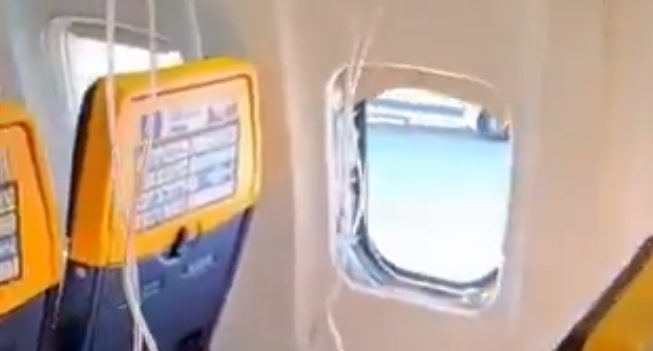 Sauerstoffmasken hängen in einer Ryanair-Kabine neben einem geöffneten Flugzeugfenster.