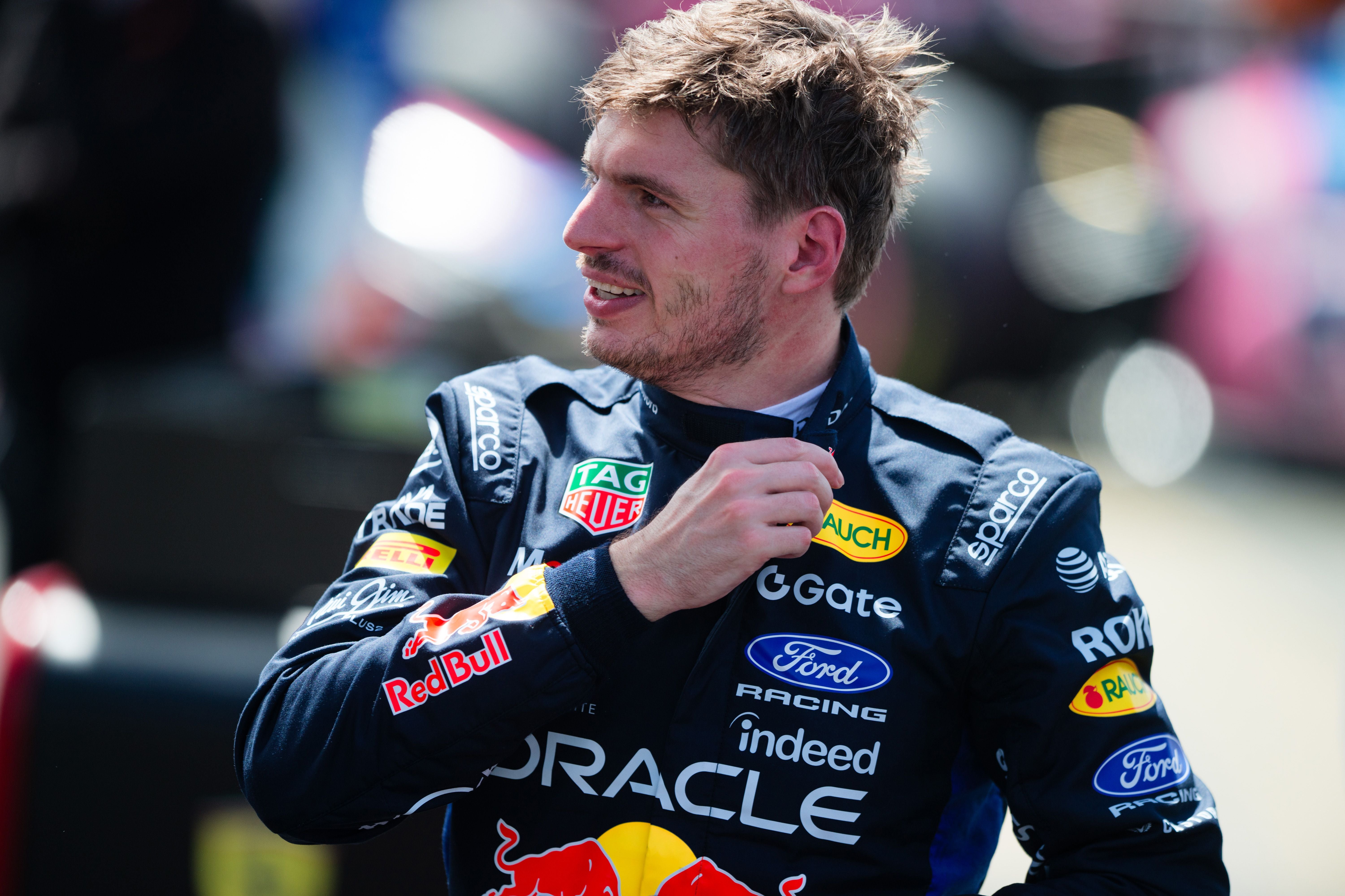 Ein Rennfahrer im Red-Bull-Rennanzug lächelt und schaut zur Seite.