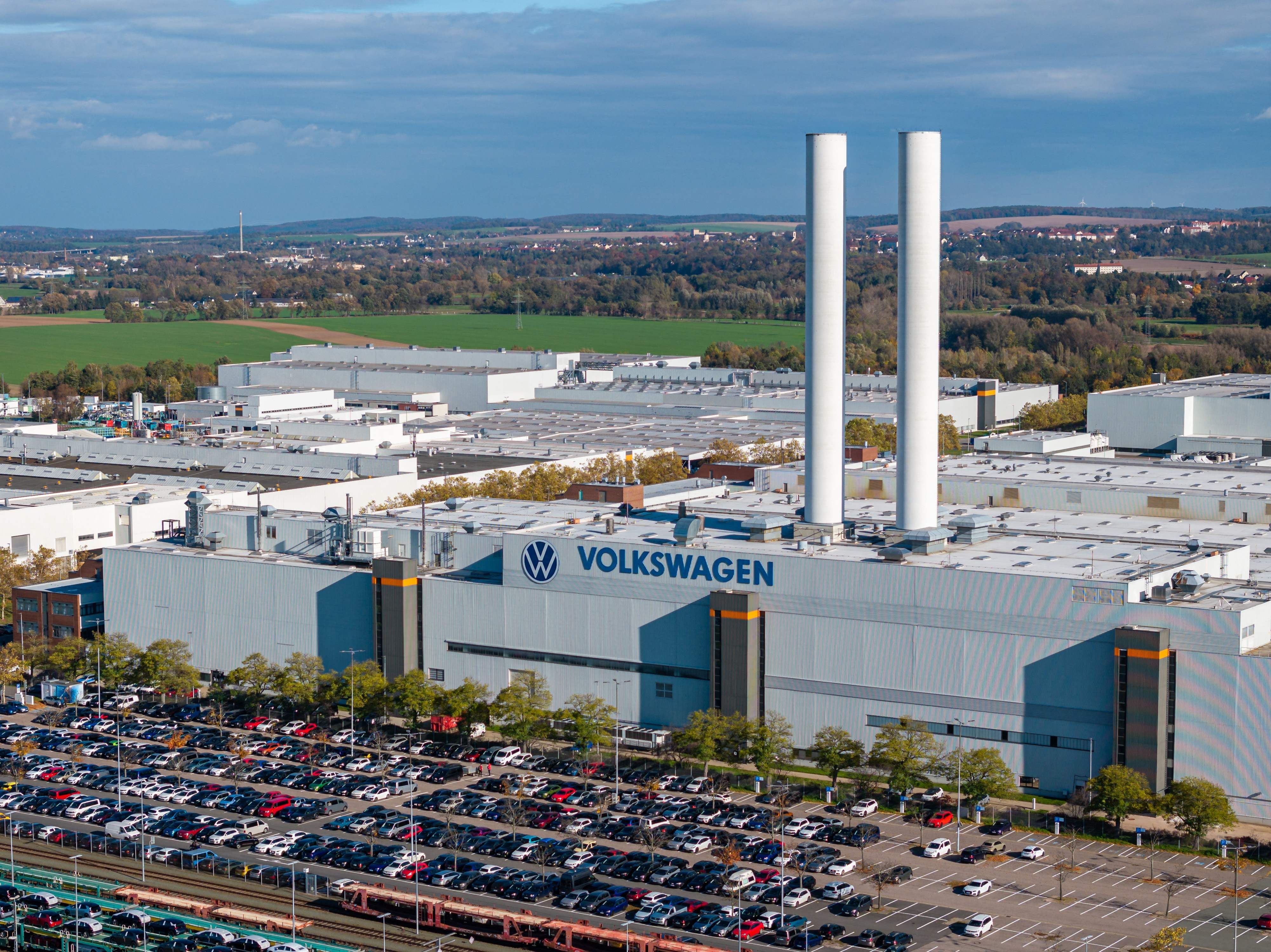 Luftaufnahme des Volkswagen-Werks in Zwickau mit vielen geparkten Autos und zwei hohen Schornsteinen.