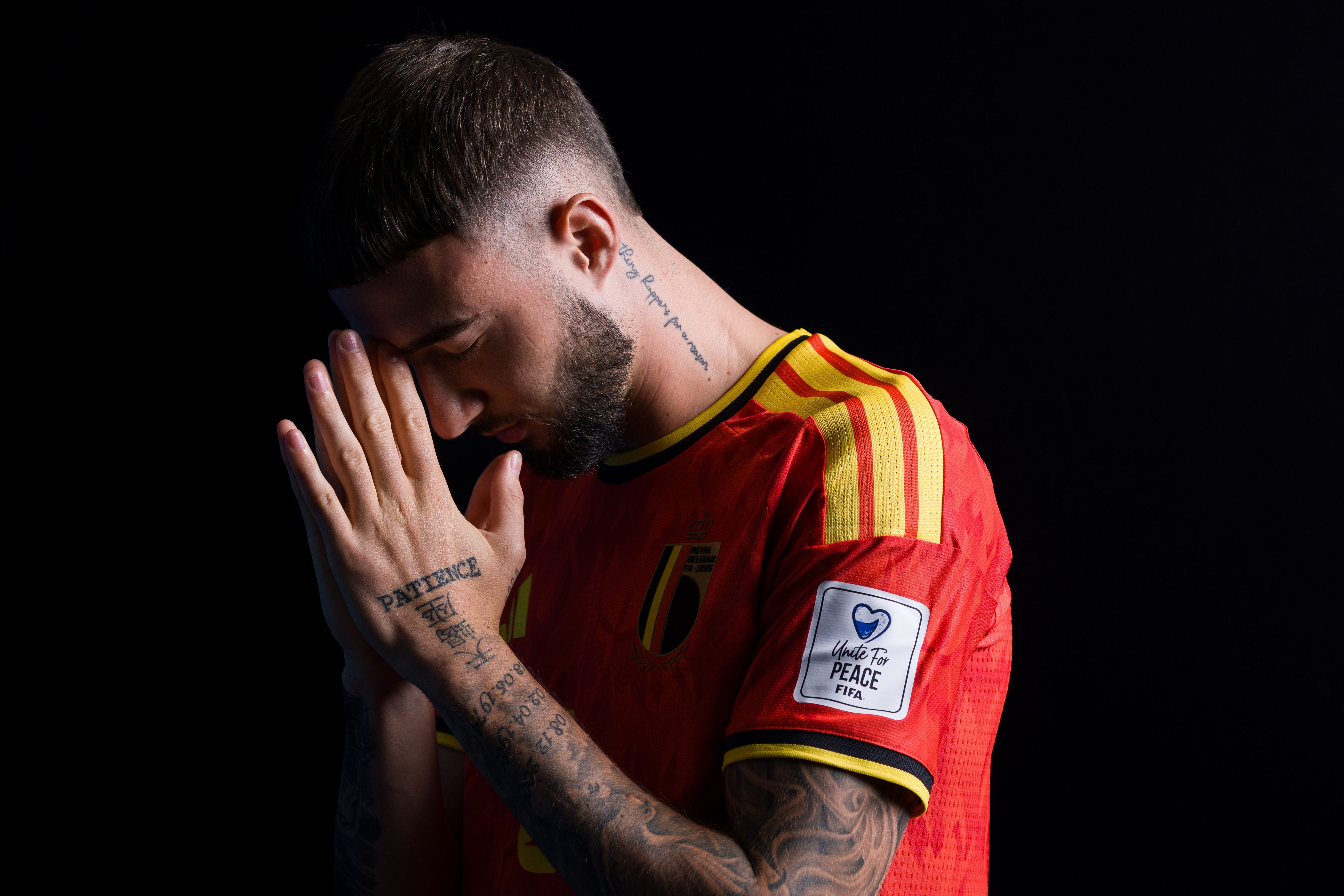 Ein Fußballspieler im Belgien-Trikot steht betend mit geschlossenen Augen und gefalteten Händen.