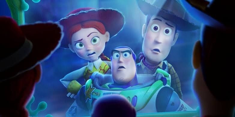 Drei Spielzeugfiguren aus Toy Story schauen überrascht auf eine leuchtende Fläche.