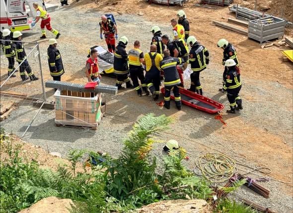 Mehrere Feuerwehrleute retten eine Person bei einem Unfall auf einer Baustelle.