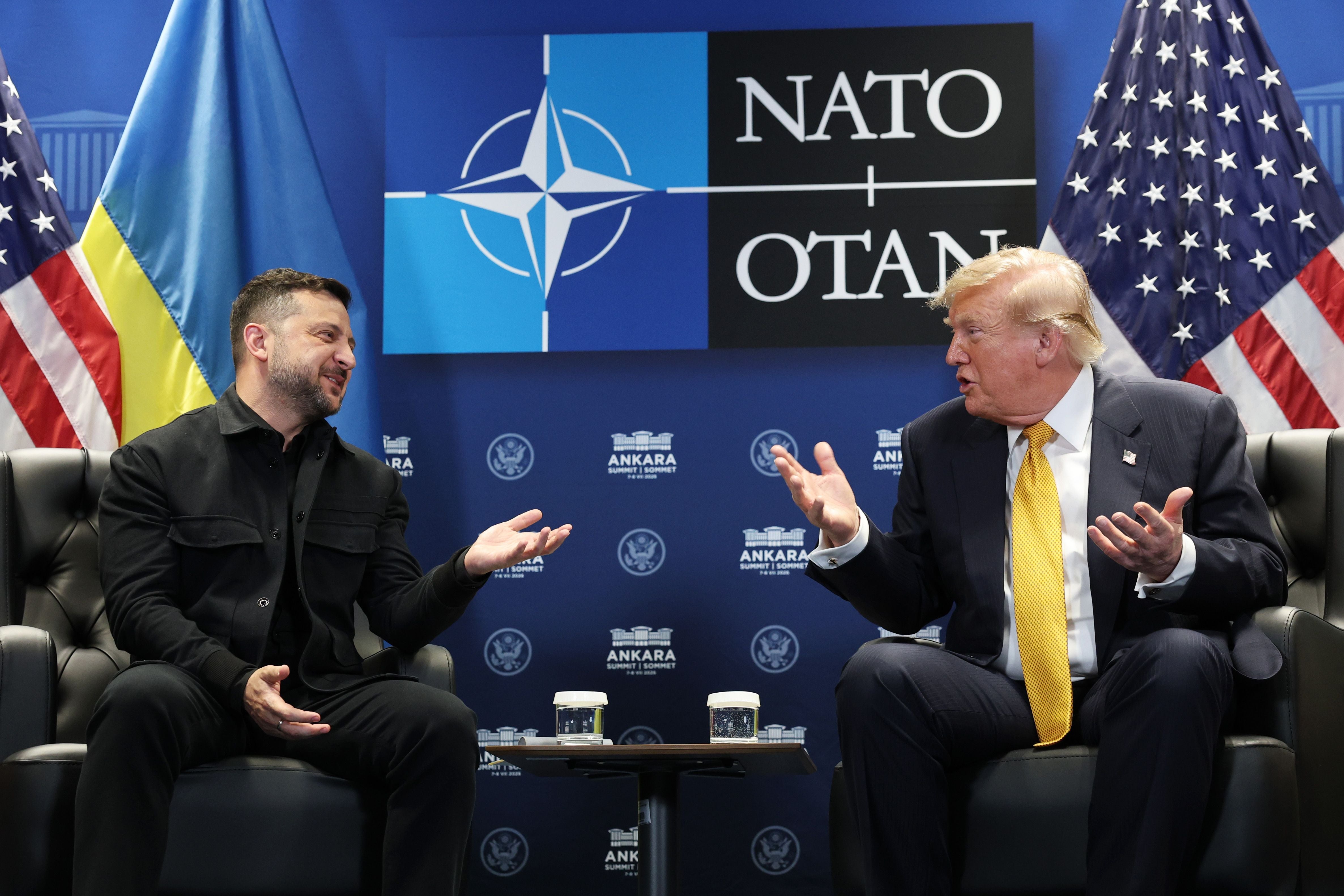 Donald Trump und Wolodymyr Selenskyj unterhalten sich beim NATO-Gipfel, hinter ihnen Flaggen.