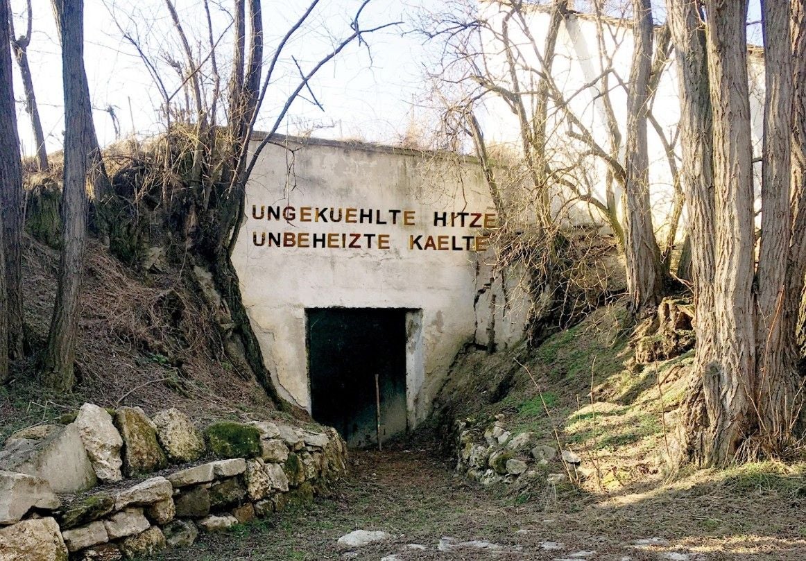 Eingang zu einem Bunker mit der Aufschrift „UNGEKUEHLTE HITZE UNBEHEIZTE KAELTE“.