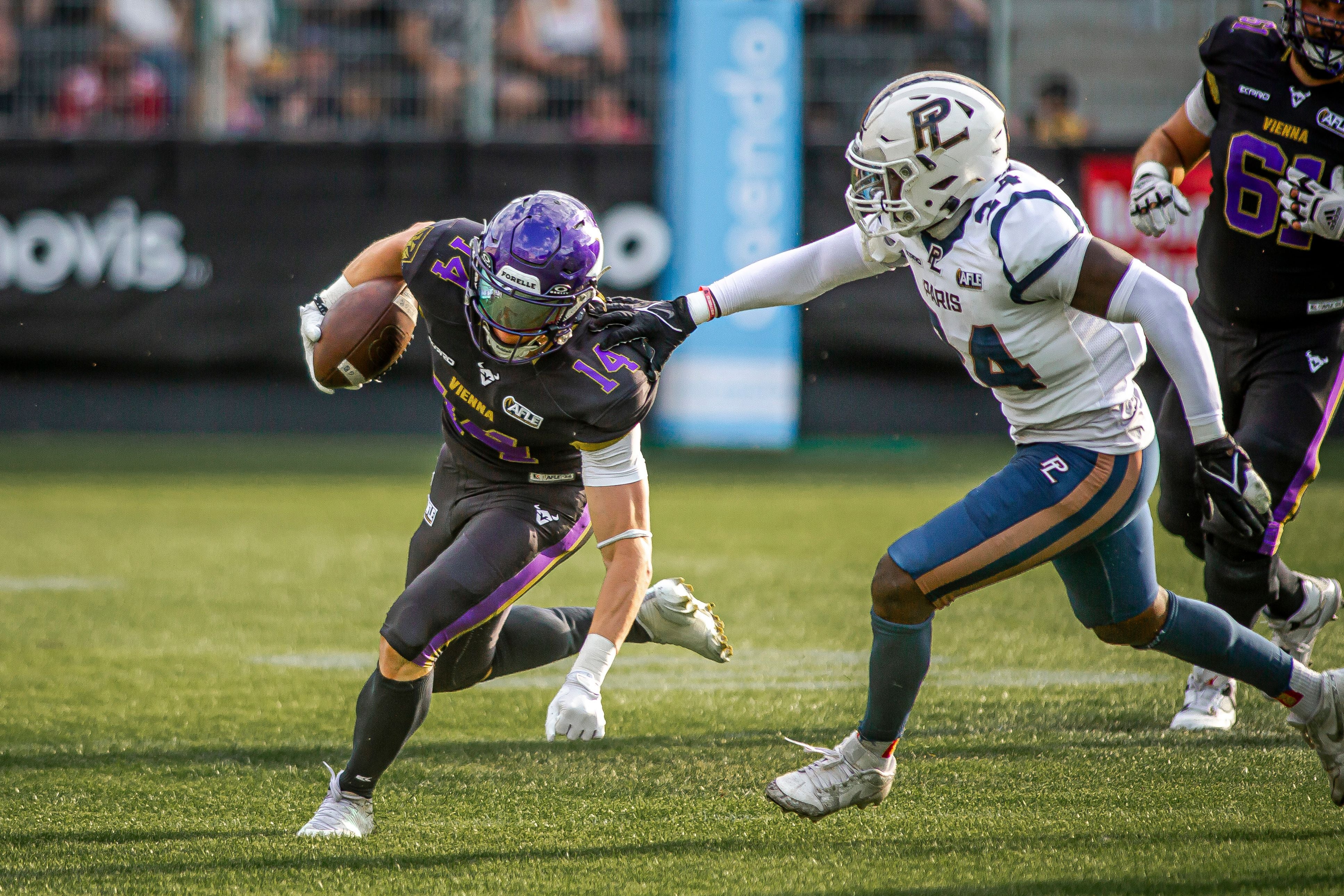 Ein Footballspieler der Vikings entkommt einem Verteidiger der Paris Lights auf dem Spielfeld.