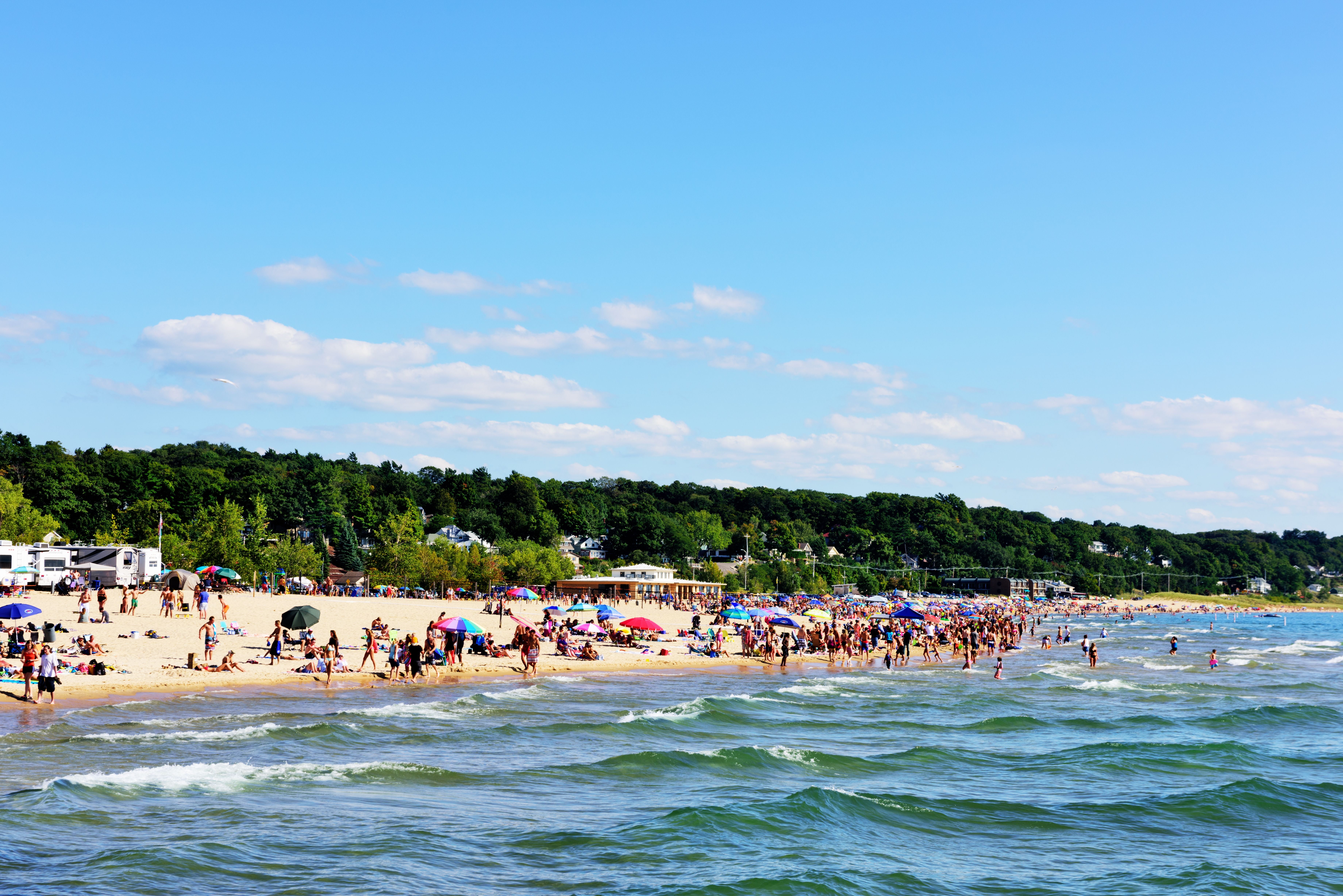 Voller Sandstrand an einem Sommertag in Grand Haven State Park am Lake Michigan mit vielen Menschen und Sonnenschirmen.