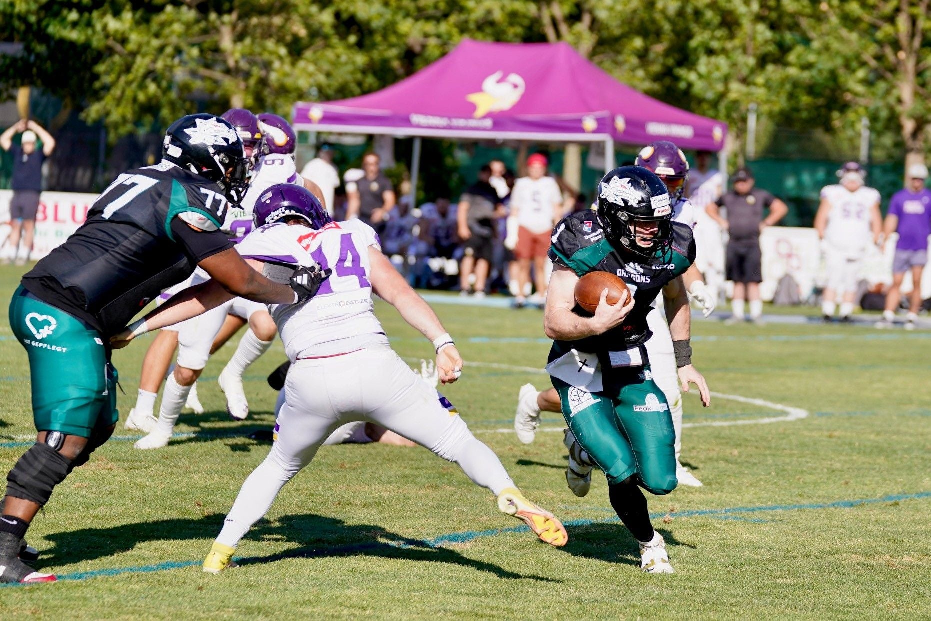 Ein Dragons-Spieler läuft mit dem Football, während ein Vikings-Spieler ihn zu stoppen versucht.