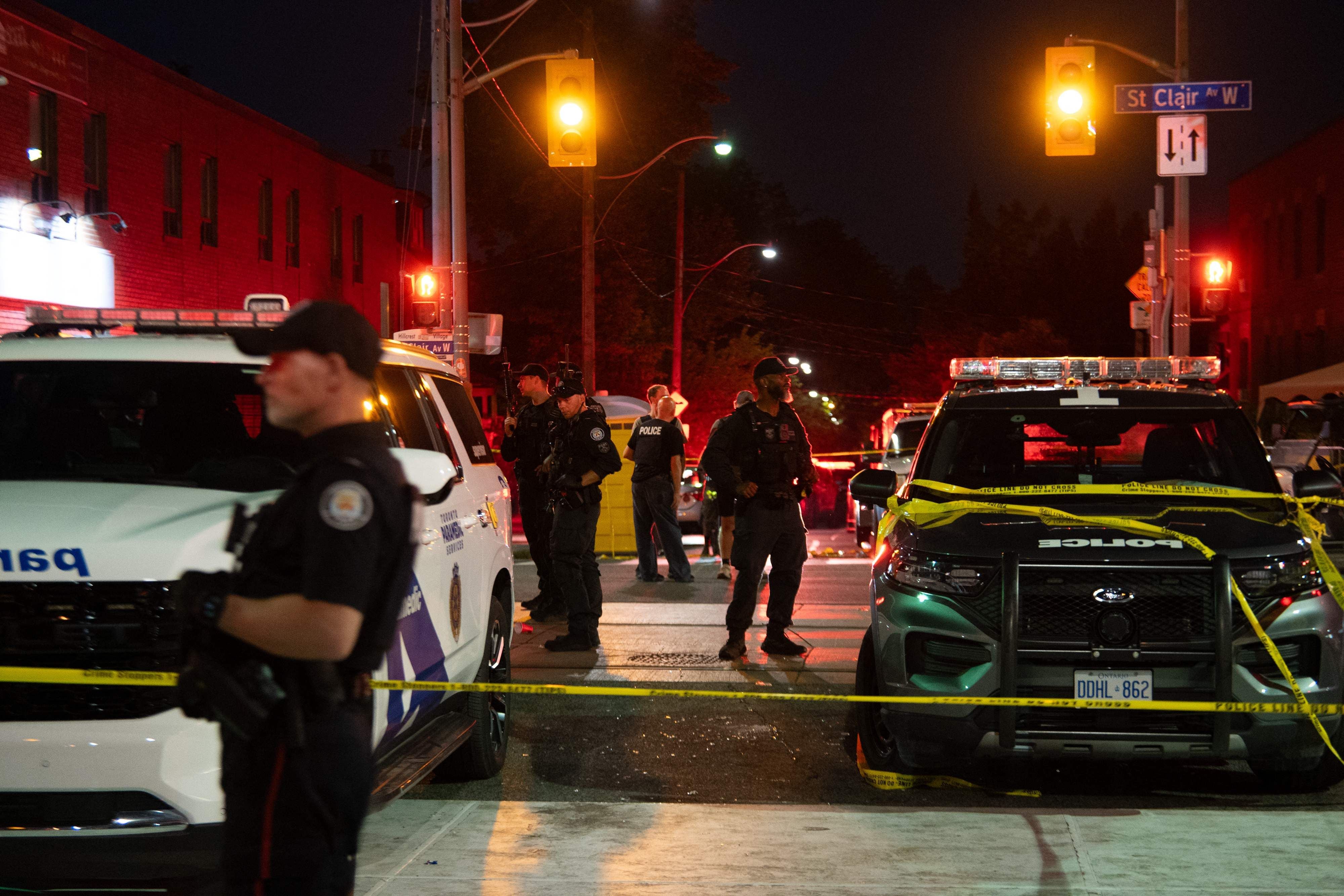 Polizisten sperren nachts eine Straße mit Absperrband an einem Tatort in Toronto ab.