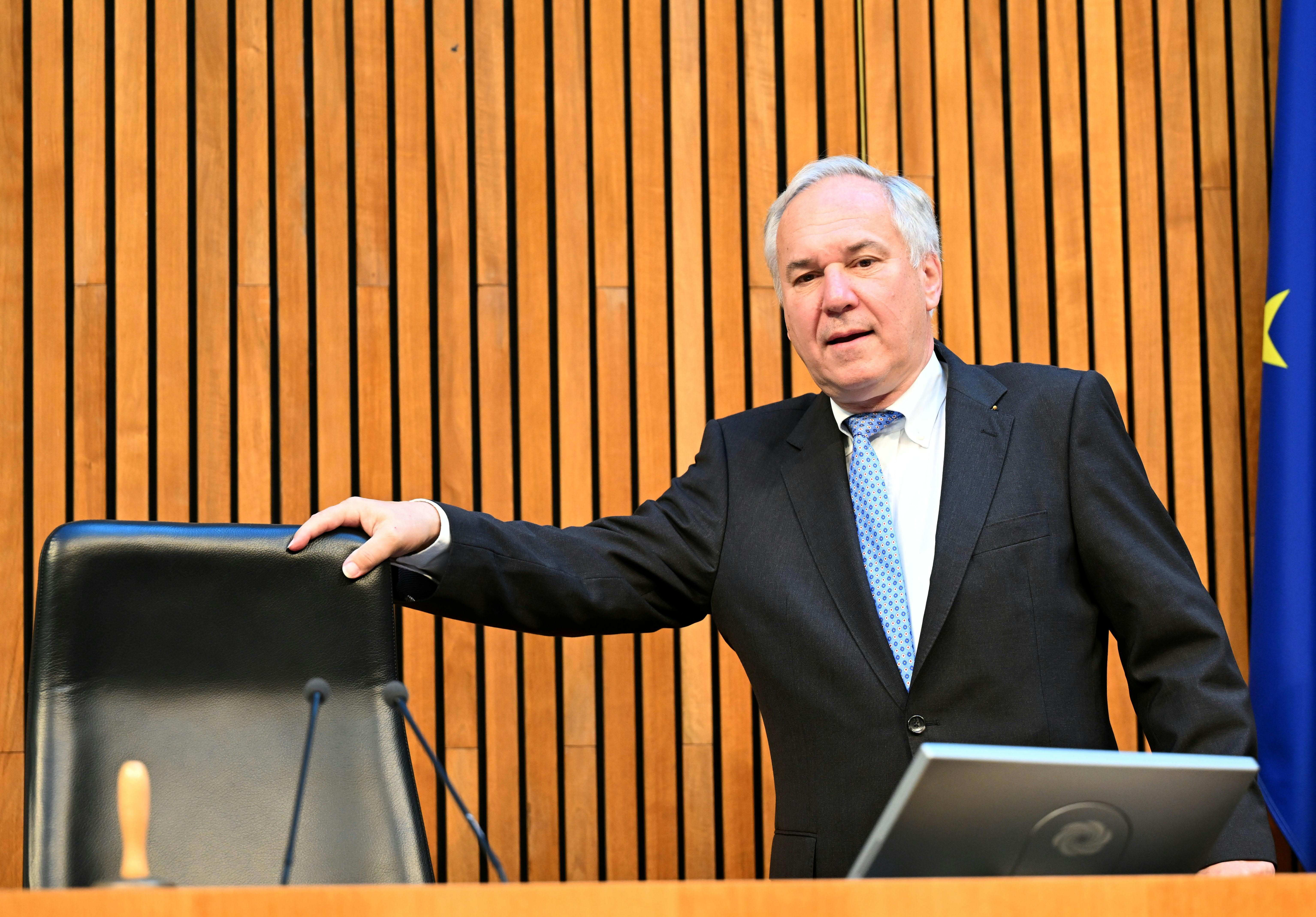 Ein Mann im Anzug steht im Parlament vor einer Holzvertäfelung und spricht am Rednerpult.