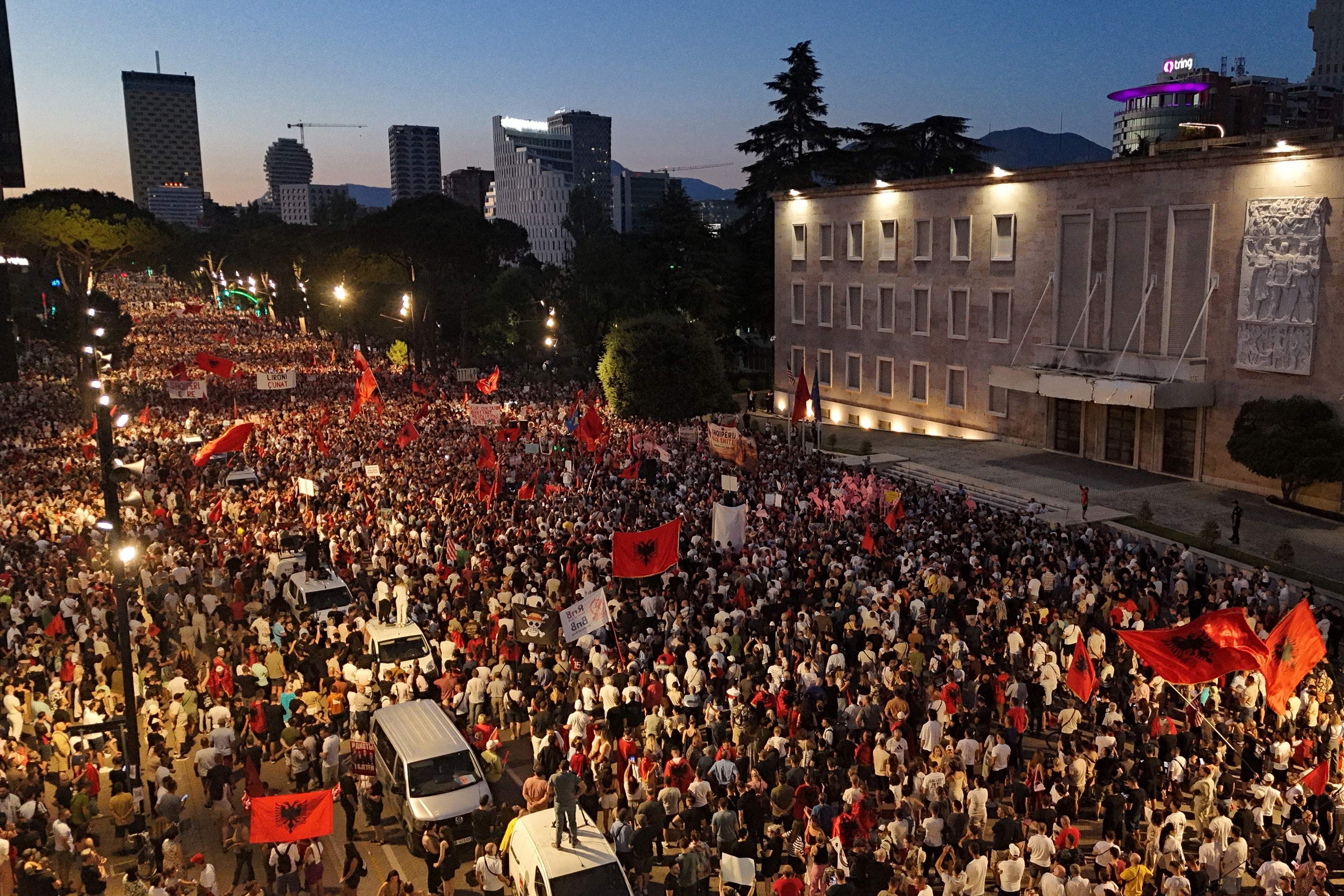 Große Menschenmenge demonstriert abends vor dem Regierungsgebäude in Tirana mit albanischen Flaggen.