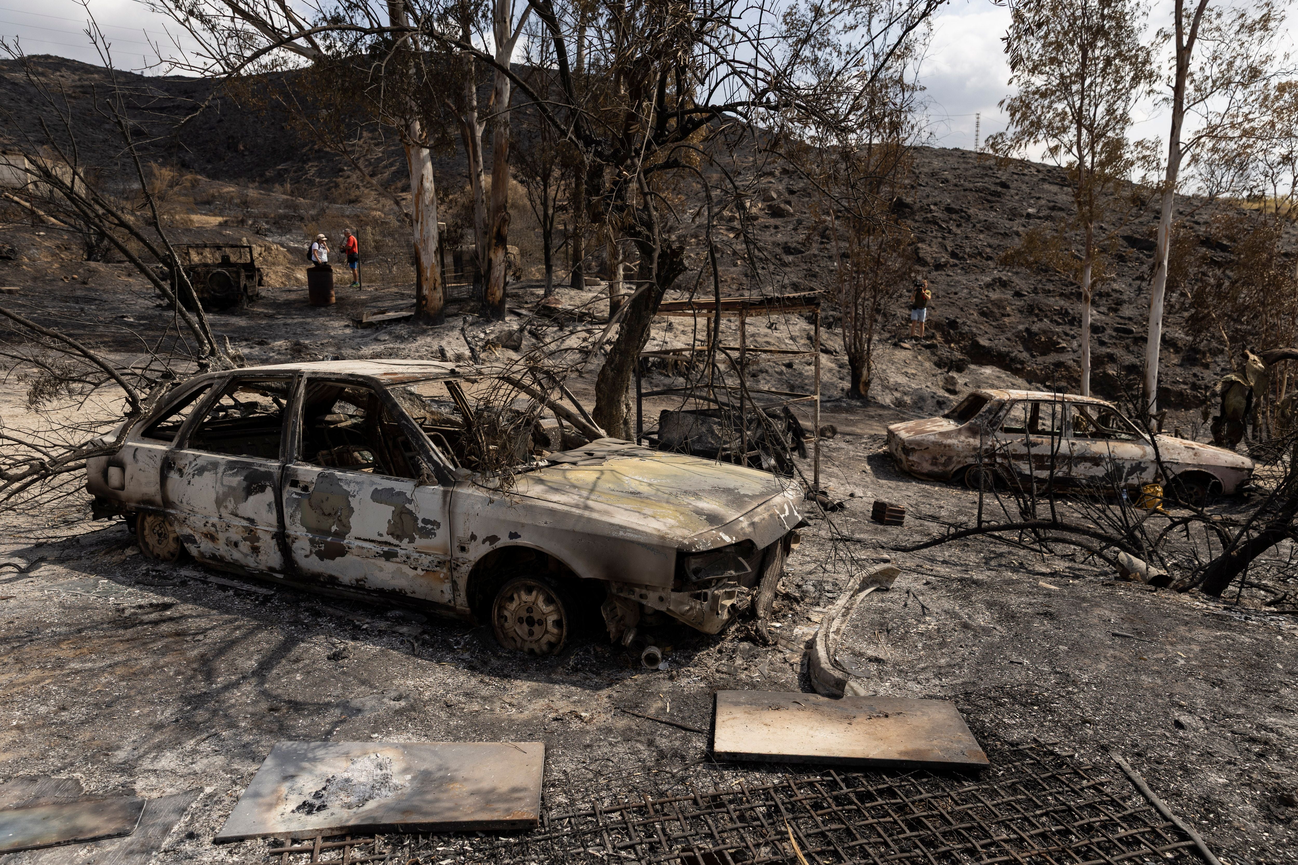 Ausgebrannte Autos stehen in einer verkohlten, von Feuer zerstörten Landschaft in Almería, Spanien.
