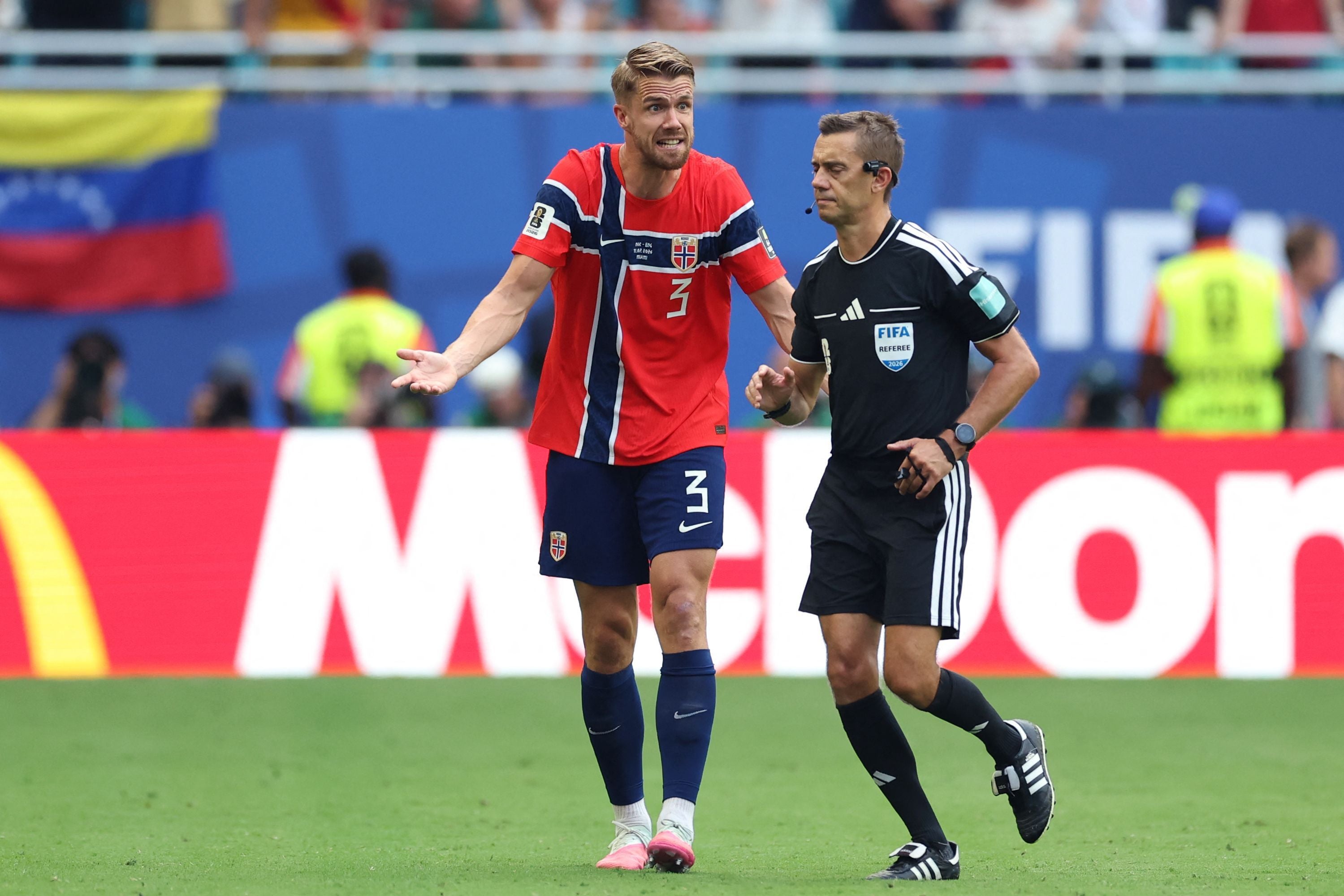 Ein norwegischer Fußballspieler diskutiert mit einem Schiedsrichter während eines Spiels.