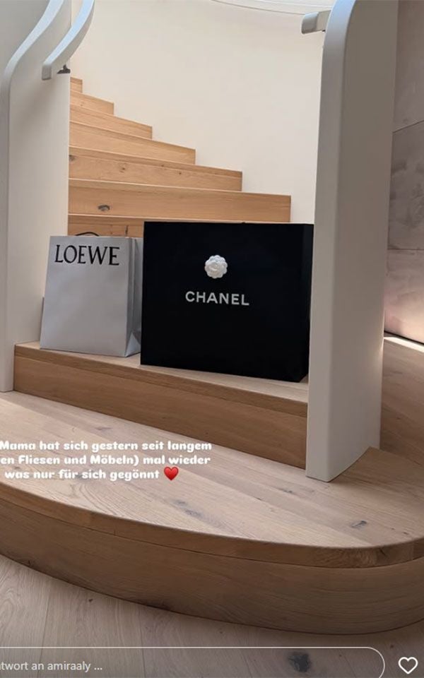 Zwei Einkaufstüten von LOEWE und CHANEL stehen auf einer hölzernen Treppe.