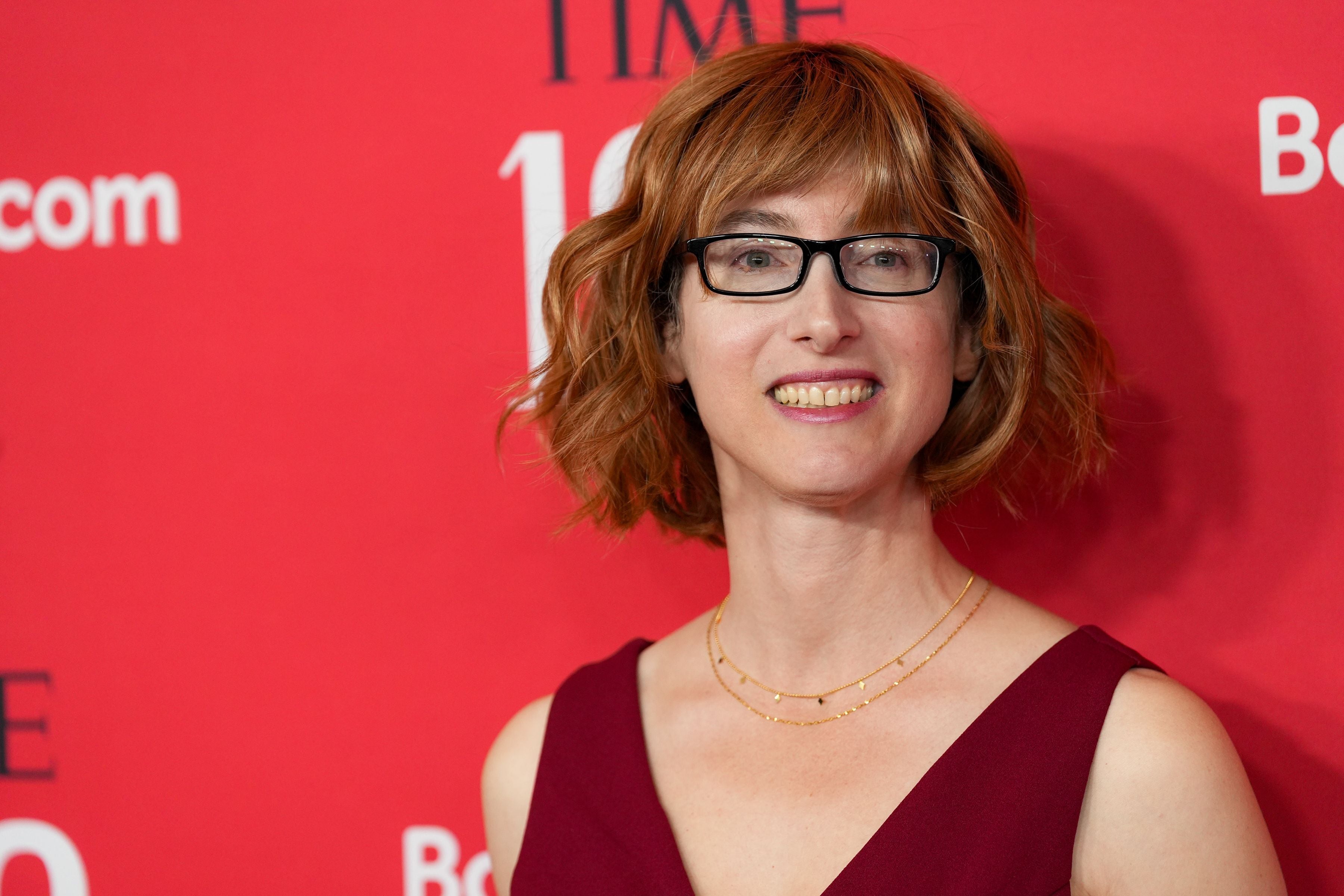 Frau mit Brille und kurzem, braunem Haar vor rotem Hintergrund auf einer Gala.
