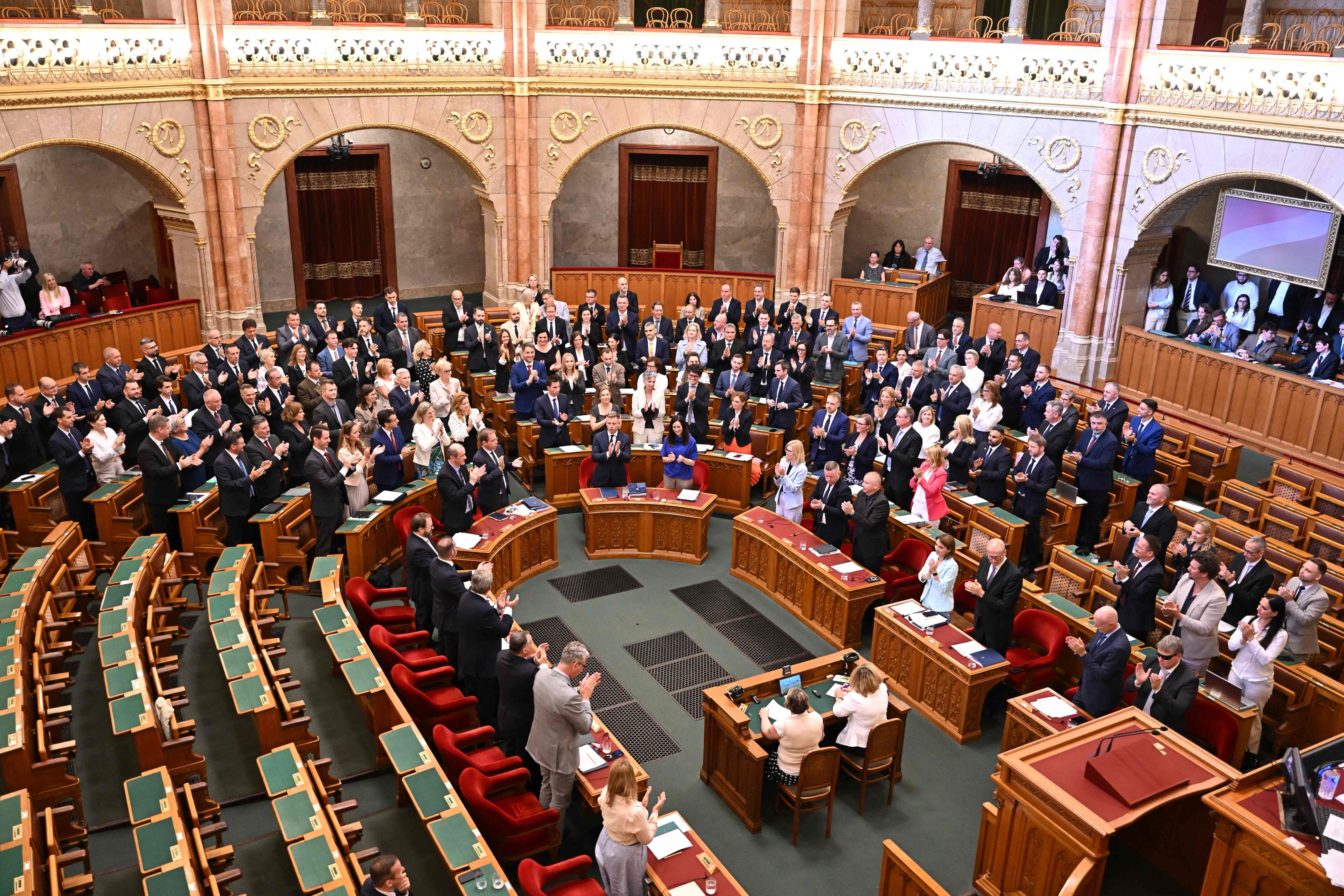 Abgeordnete im ungarischen Parlament stehen und applaudieren nach einer Abstimmung im Plenarsaal.