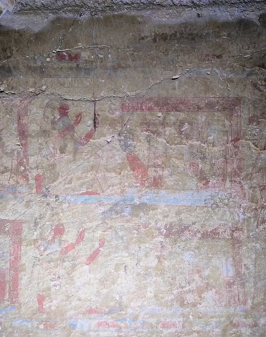 Verblasste altägyptische Wandmalerei mit roten und blauen Figuren und Hieroglyphen.