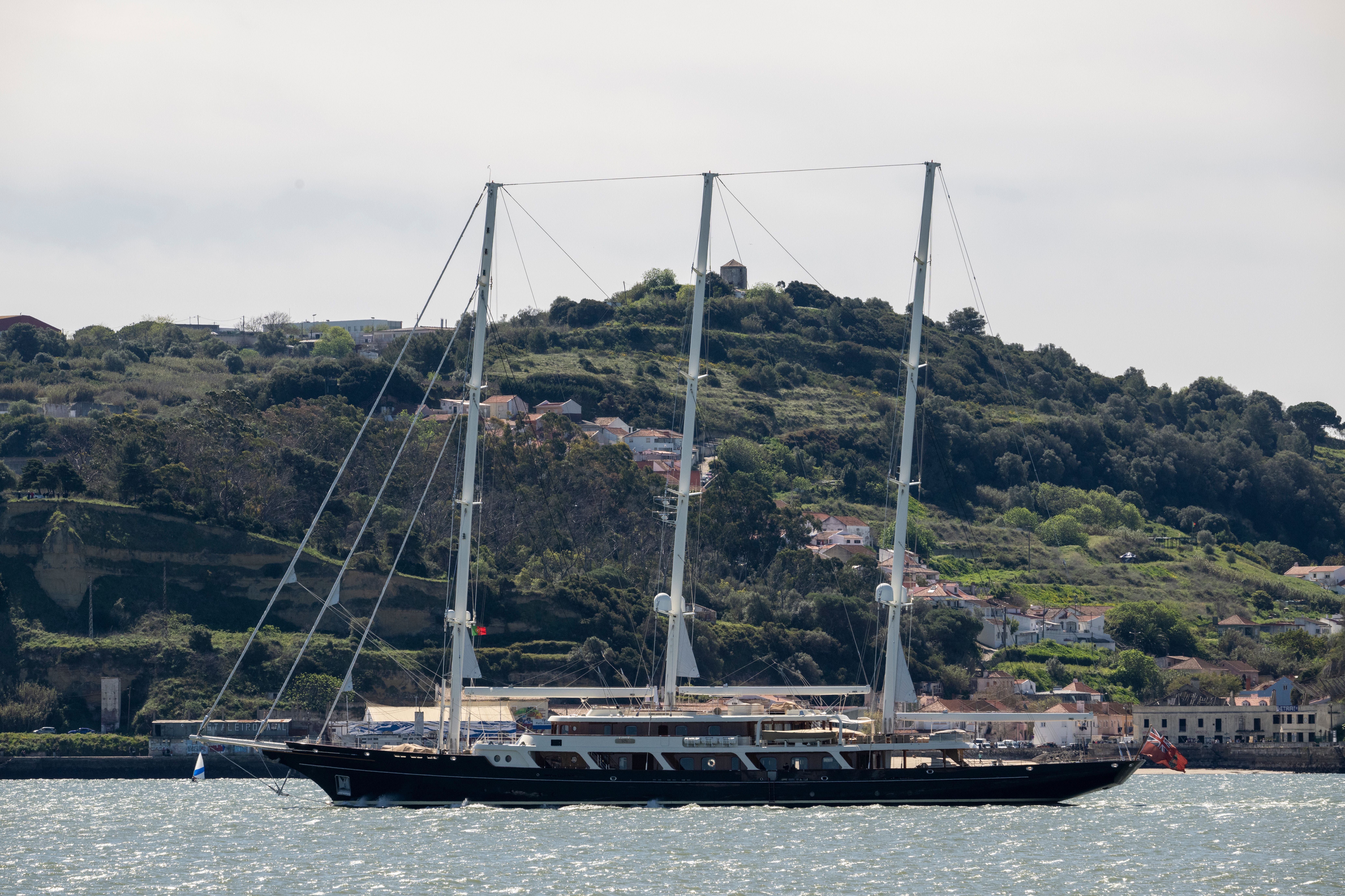 Dreimastige Segelyacht Eos segelt auf dem Fluss Tagus vor grüner Hügellandschaft in Lissabon.