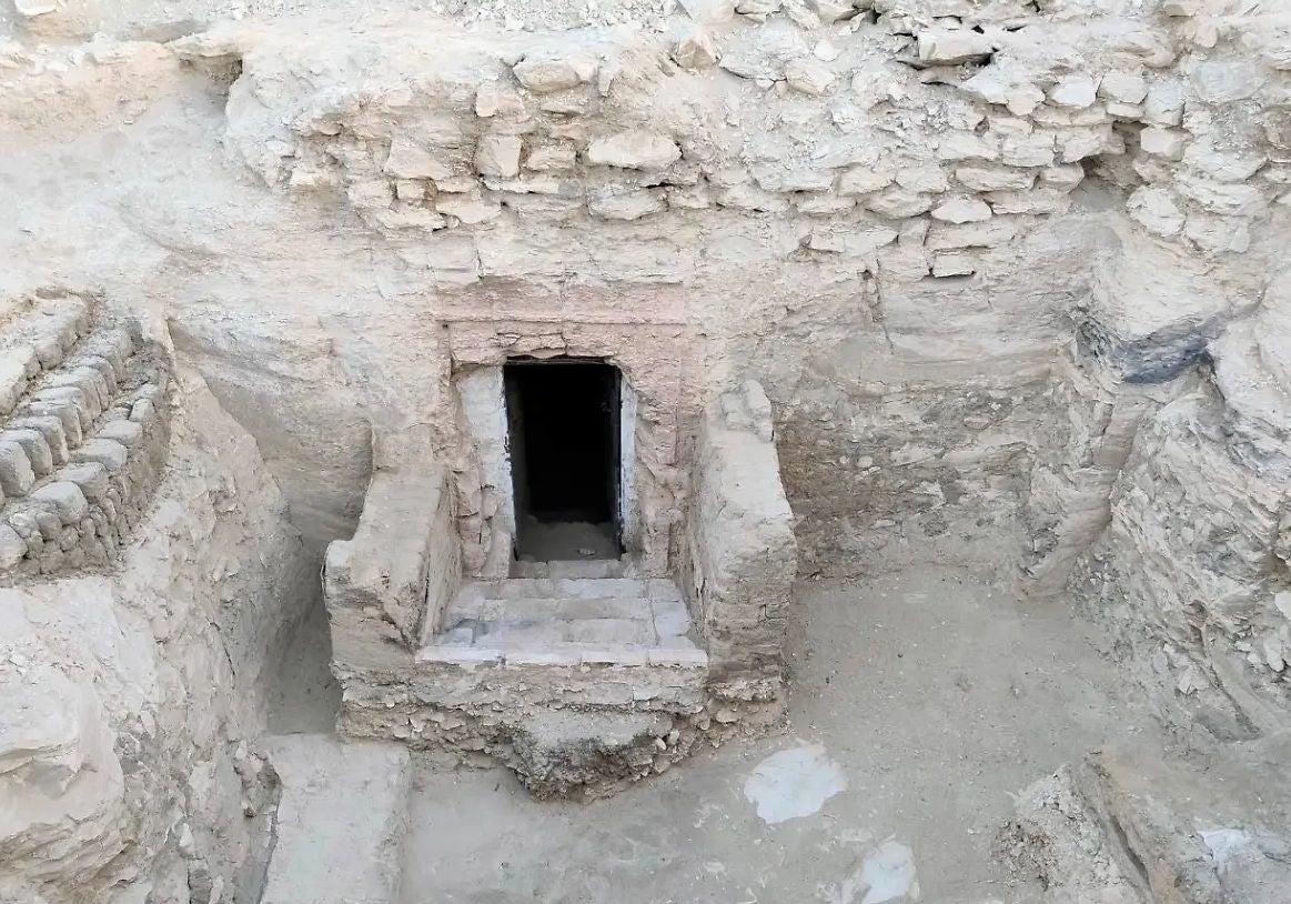Eingang einer antiken Grabkammer in Ägypten aus Stein und Lehm, teilweise freigelegt.