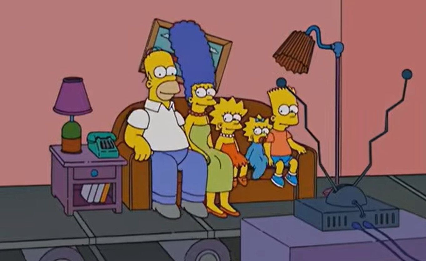 Die Simpsons sitzen auf dem Sofa und schauen gemeinsam fern im Wohnzimmer.