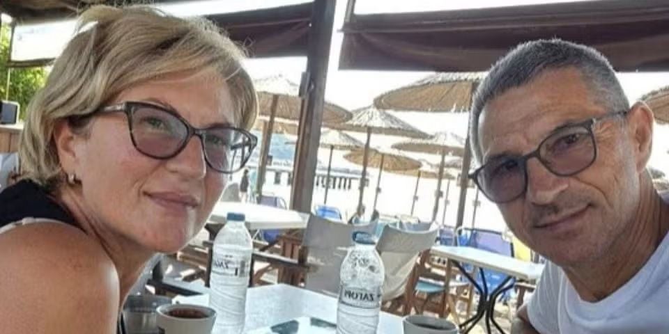 Ein Mann und eine Frau sitzen an einem Strandcafé mit Wasserflaschen und Kaffee auf dem Tisch.