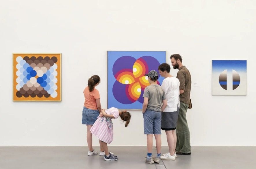 Fünf Personen betrachten bunte abstrakte Gemälde in einer Kunstausstellung.